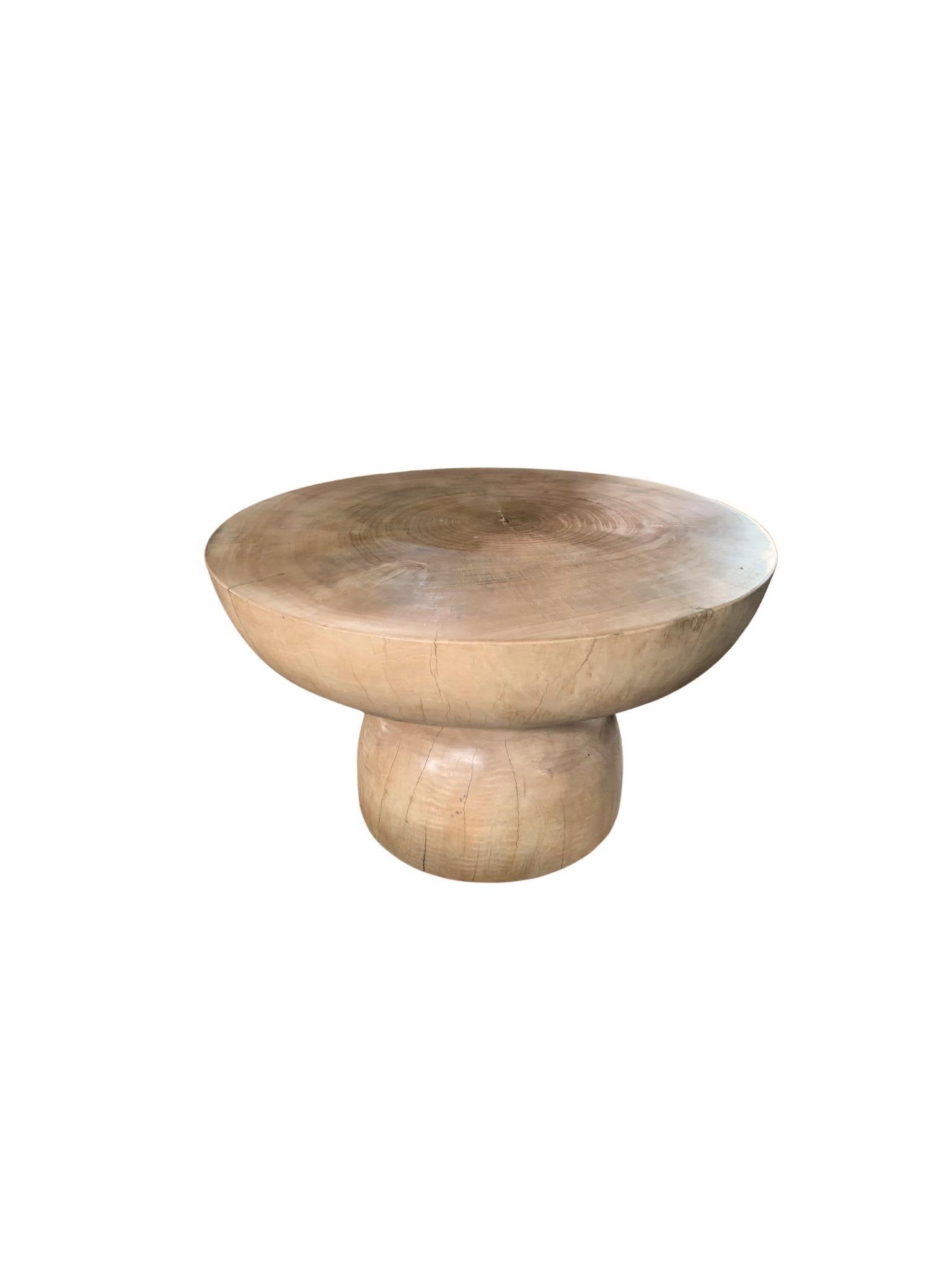 A wonderfully sculptural round side table with a sanded down finish. Its neutral pigment and wood texture makes it perfect for any space. It features a tapered base and large round table top. A uniquely sculptural and versatile piece certain to