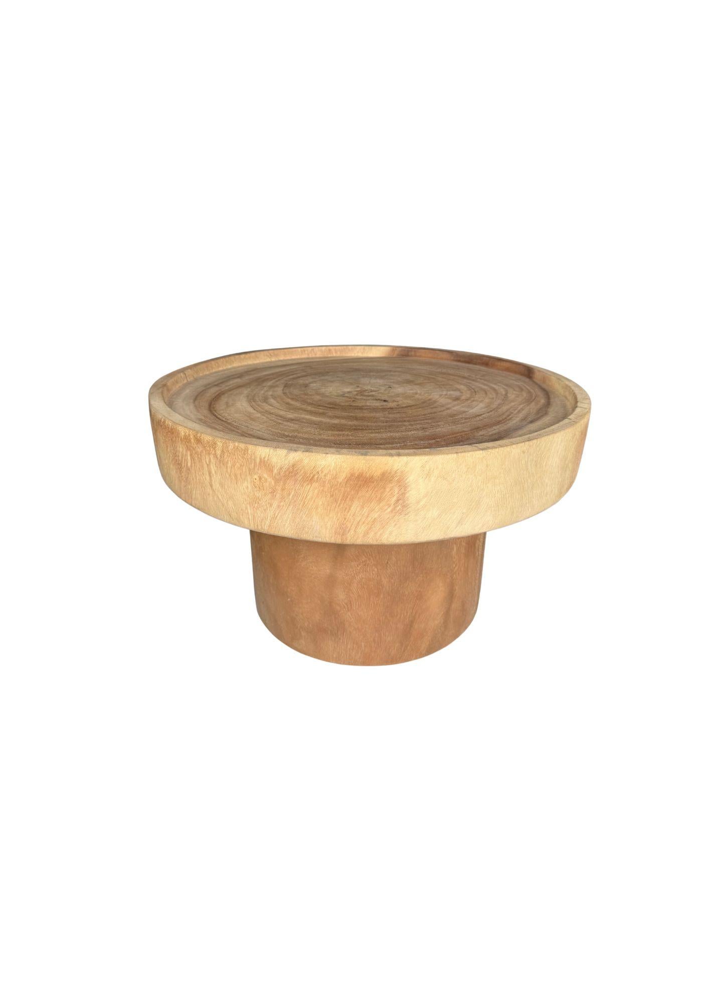 Crafted from solid mango wood, this sculptural sofa table combines bold form with natural elegance. Its smooth, rounded silhouette highlights the organic grain patterns of the wood. The wide tabletop rests on a sturdy, cylindrical base carved from