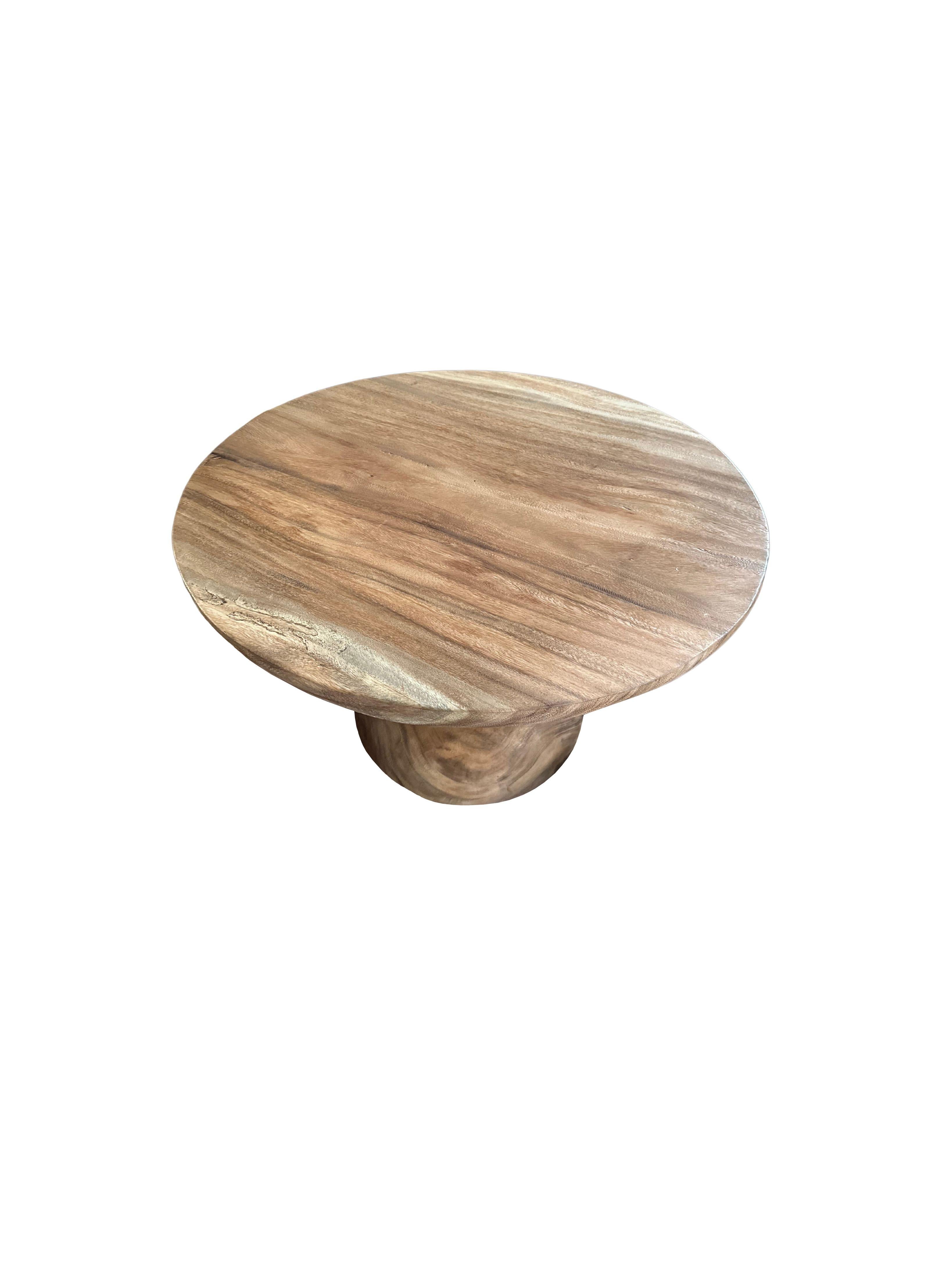 A wonderfully sculptural round side table with a sanded down finish. Its neutral pigment and wood texture makes it perfect for any space. It features a tapered base and large round table top. A uniquely sculptural and versatile piece certain to