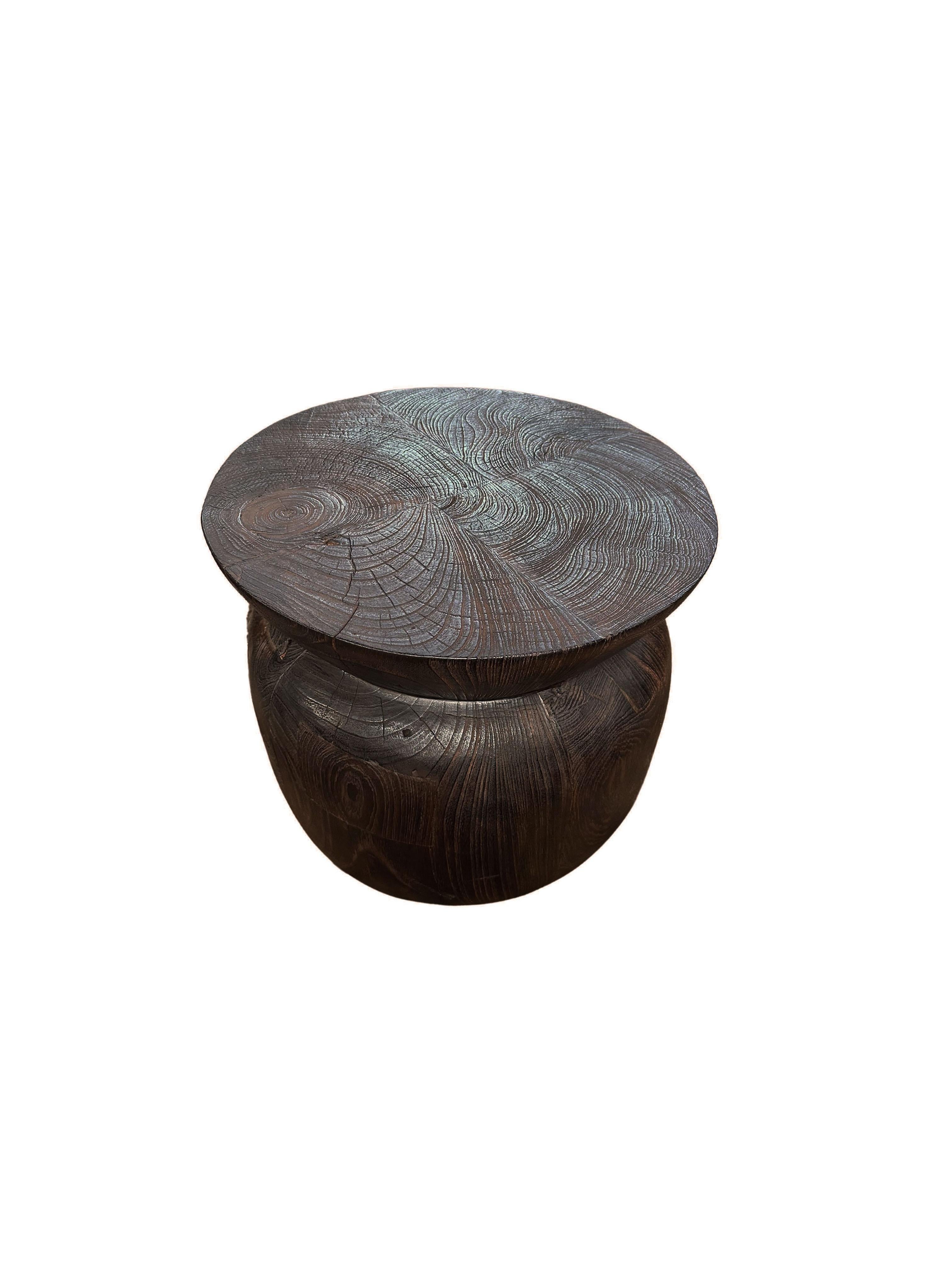 A wonderfully sculpted side table, crafted from solid teak wood. It features wonderful wood textures as well as a sculptural form. To achieve its pigment the wood was burnt several times and finished with a clear coat. 