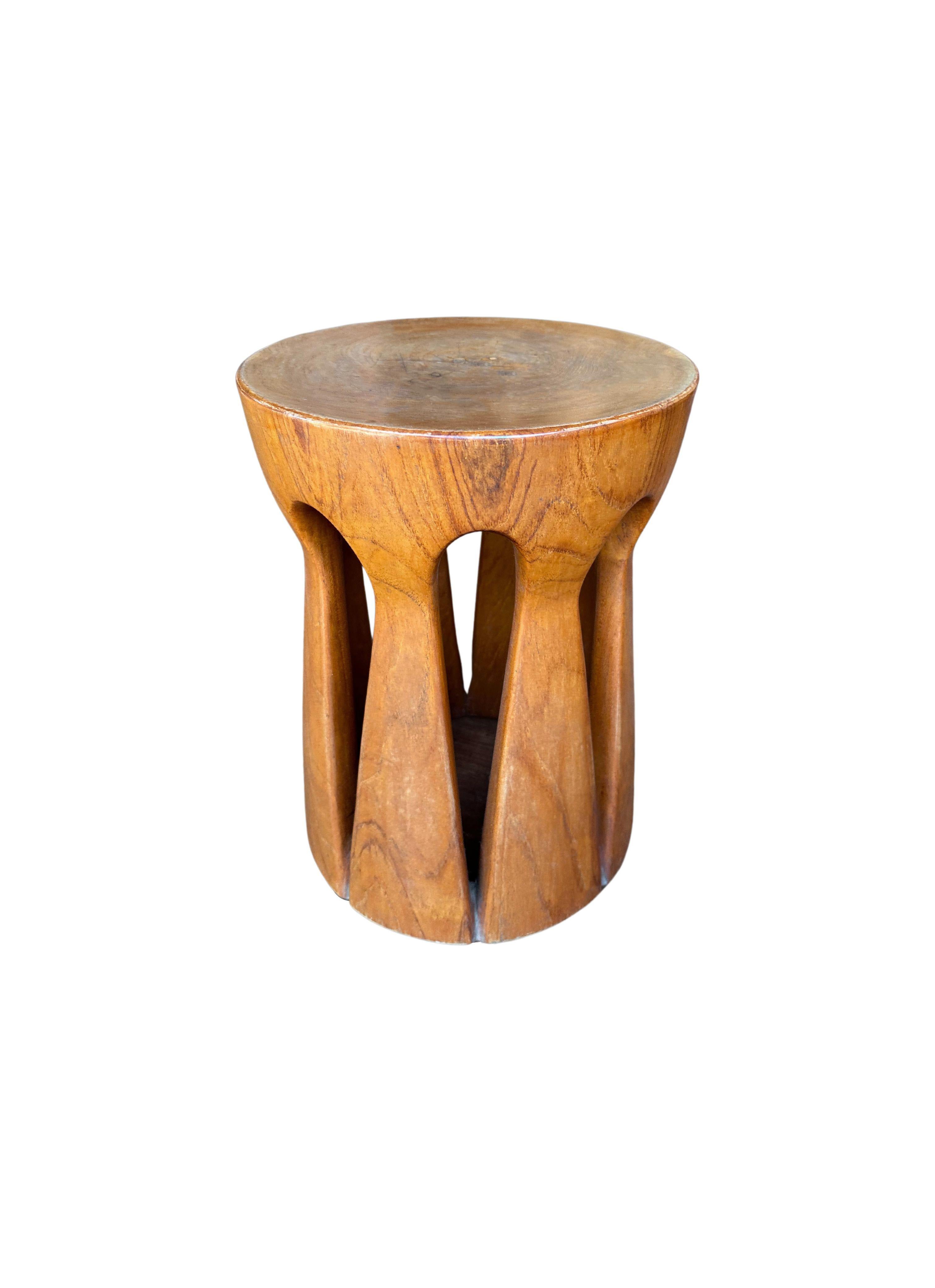 A wonderfully sculptural round teak wood stool. The stool is hollow in its center, however its unique leg structure allows it to remain robust and sturdy. Its subtle wood textures and shades make for a very elegant stool.