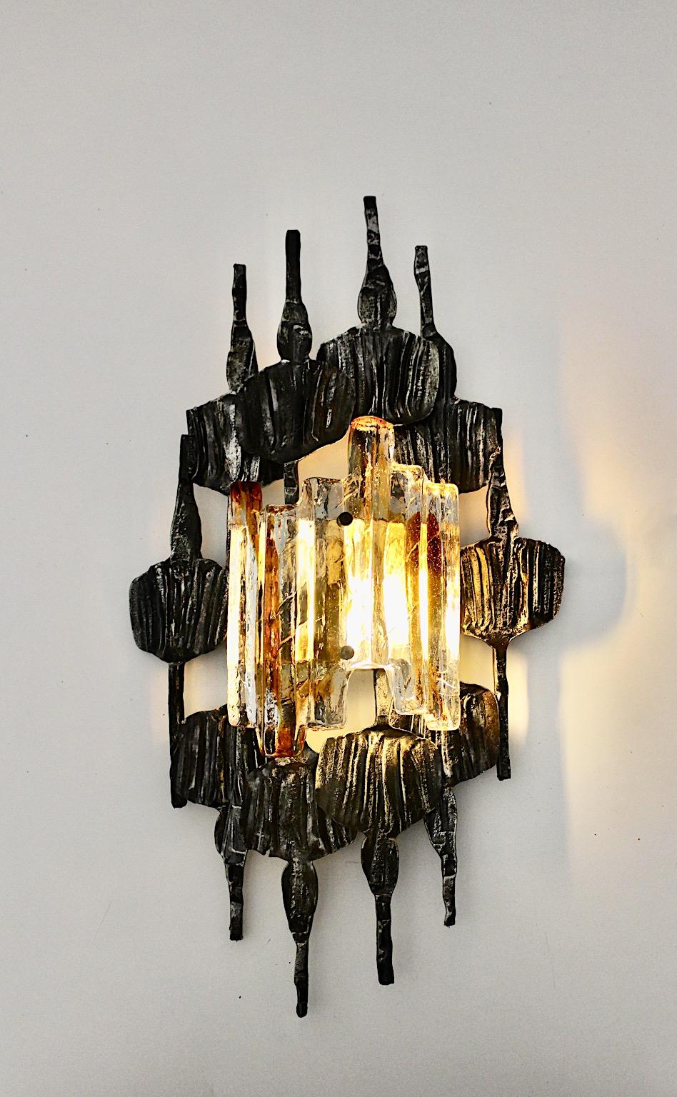 Sculptural Scandinavian Modern sconce or wall light by Tom Ahlstrom & Hans Ehrich from metal and glass 1970s Sweden.
While the sconce shows partly blacked iron frame, the shade features clear glass and glass in amber color tone.
Perfect to use the