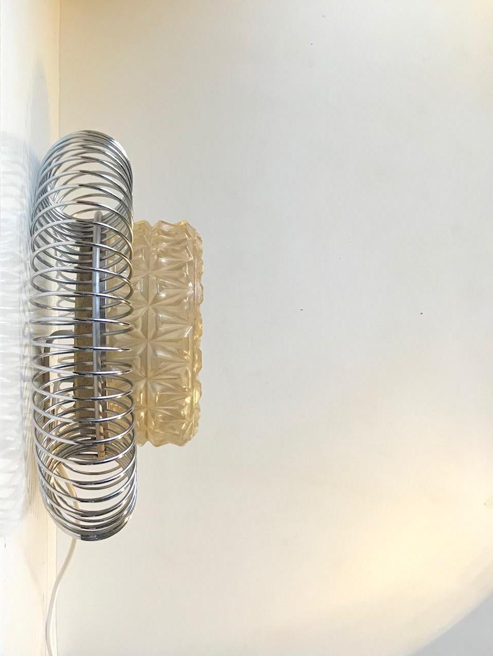 Unusual wall light with chrome-plated perimeter of spiral steel and center shade in pressed glass. It resembles a bursting sun or flower. Anonymous Scandinavian design/maker circa 1970.