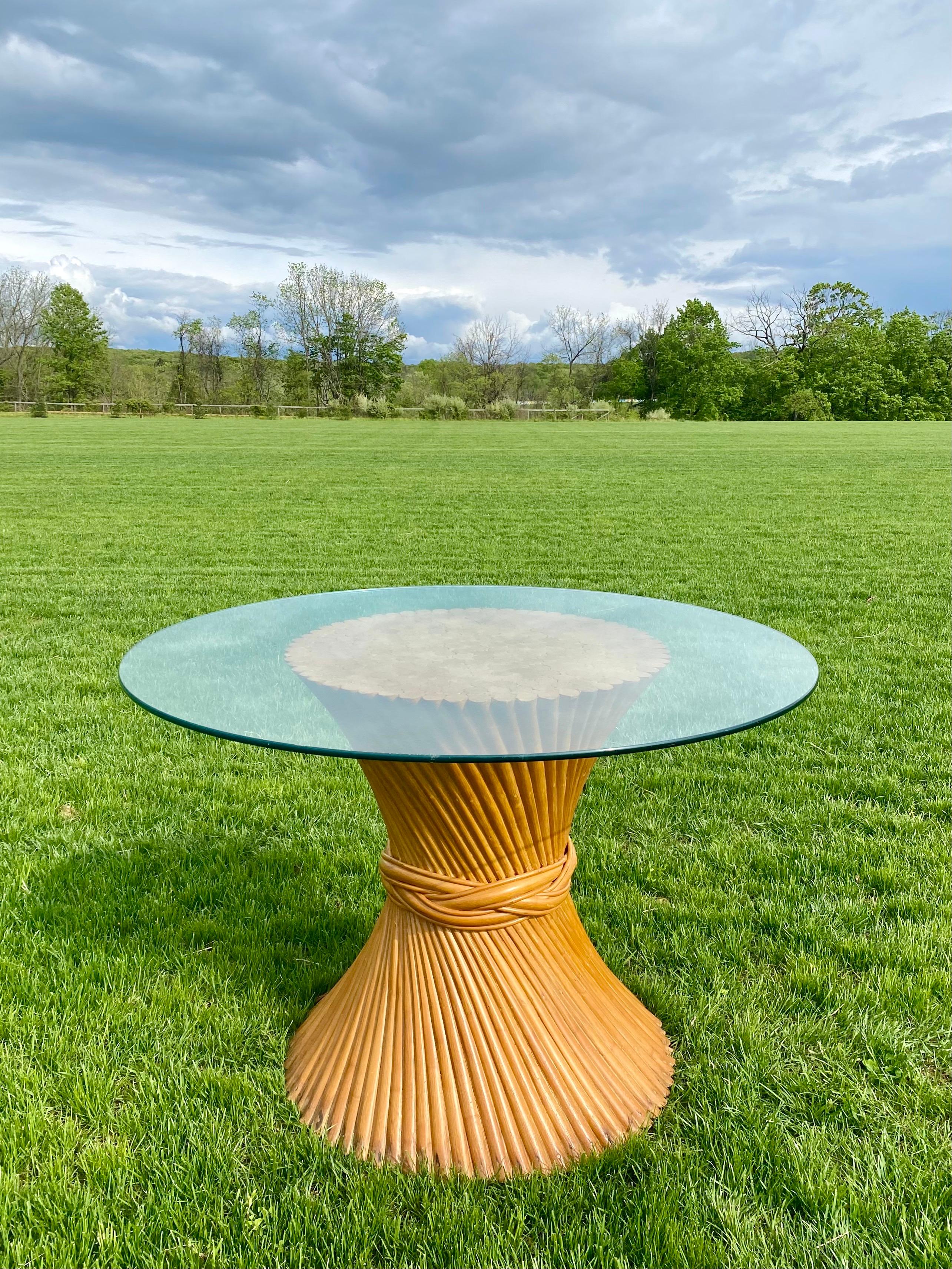 Sculptural Mid-Century Modern sheaf of wheat dining pedestal table, in the style of McGuire. This circular palm regency style table features bent and twisted rattan bamboo wood rods and round glass top. Original finish in natural tone wood with