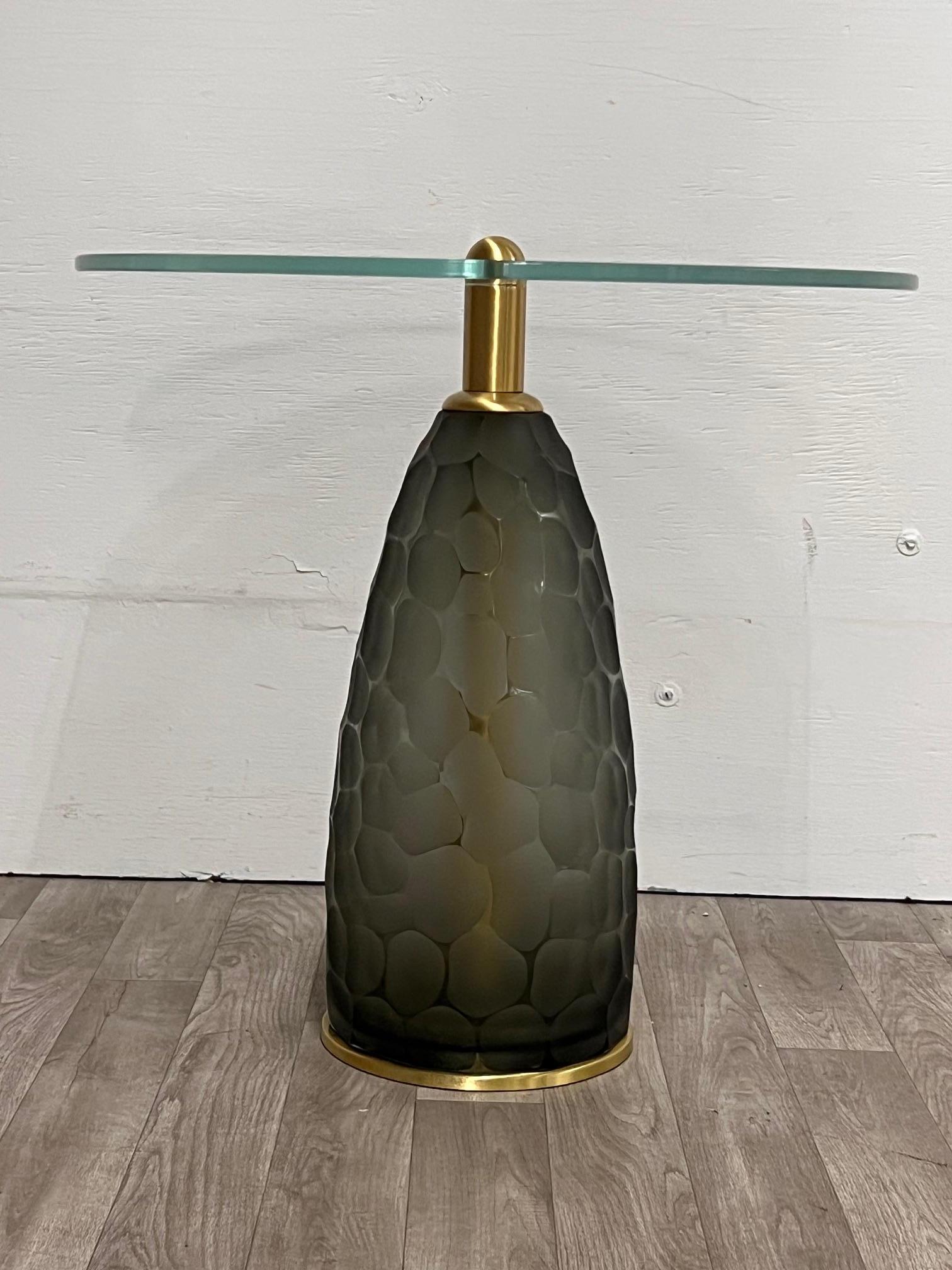 This elegant side table combines a handcrafted Murano glass base, designed by renowned glass master Alberto Donà, with a circular transparent glass top. The Murano base stands out for its delicate finish in a rock pattern that uniquely reflects