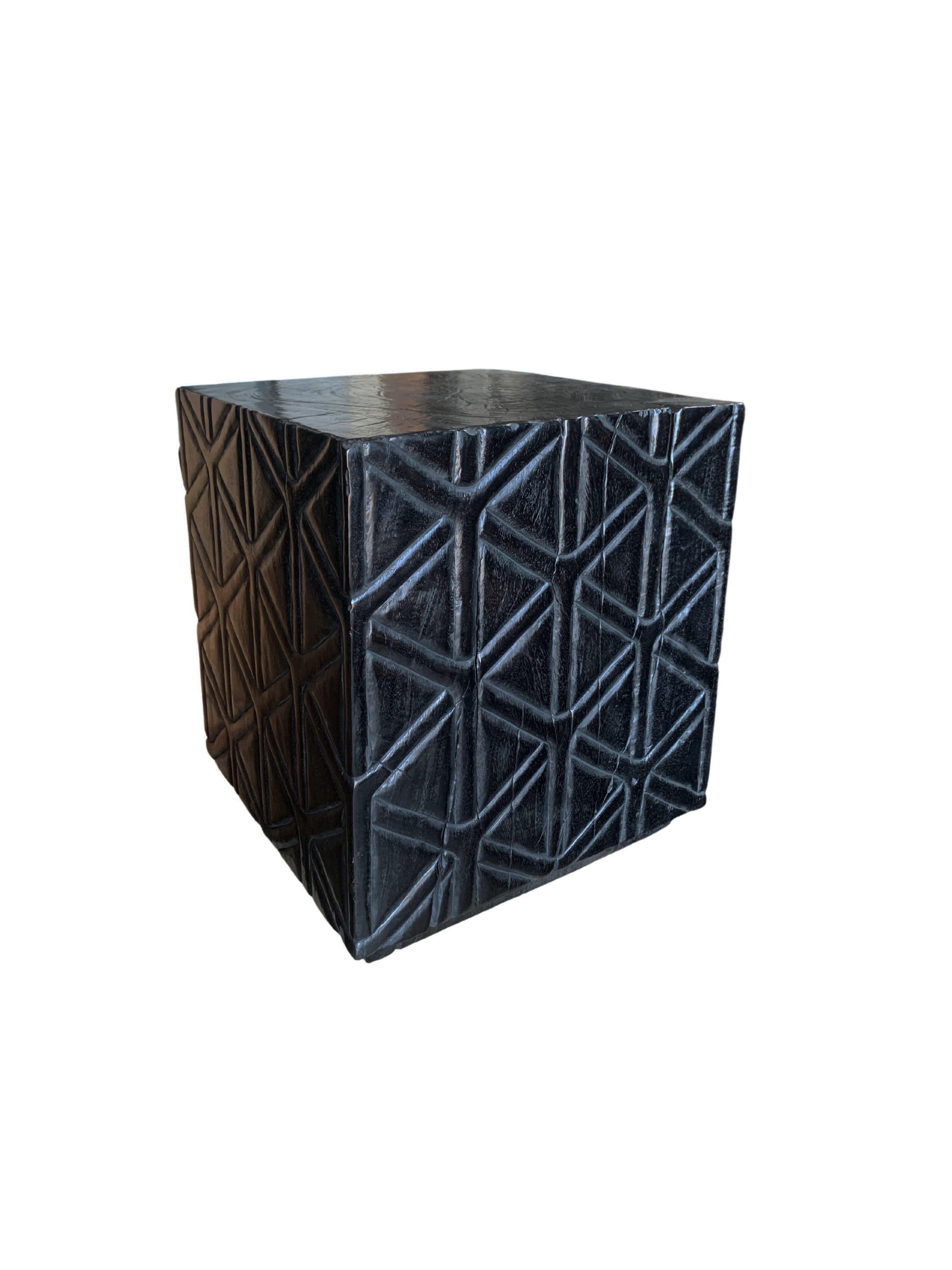 A wonderfully sculptural side table with a checkered pattern hand-carved on four sides. Its rich black pigment was achieved through burning the wood three times. Its neutral pigment and subtle wood texture makes it perfect for any space. A uniquely