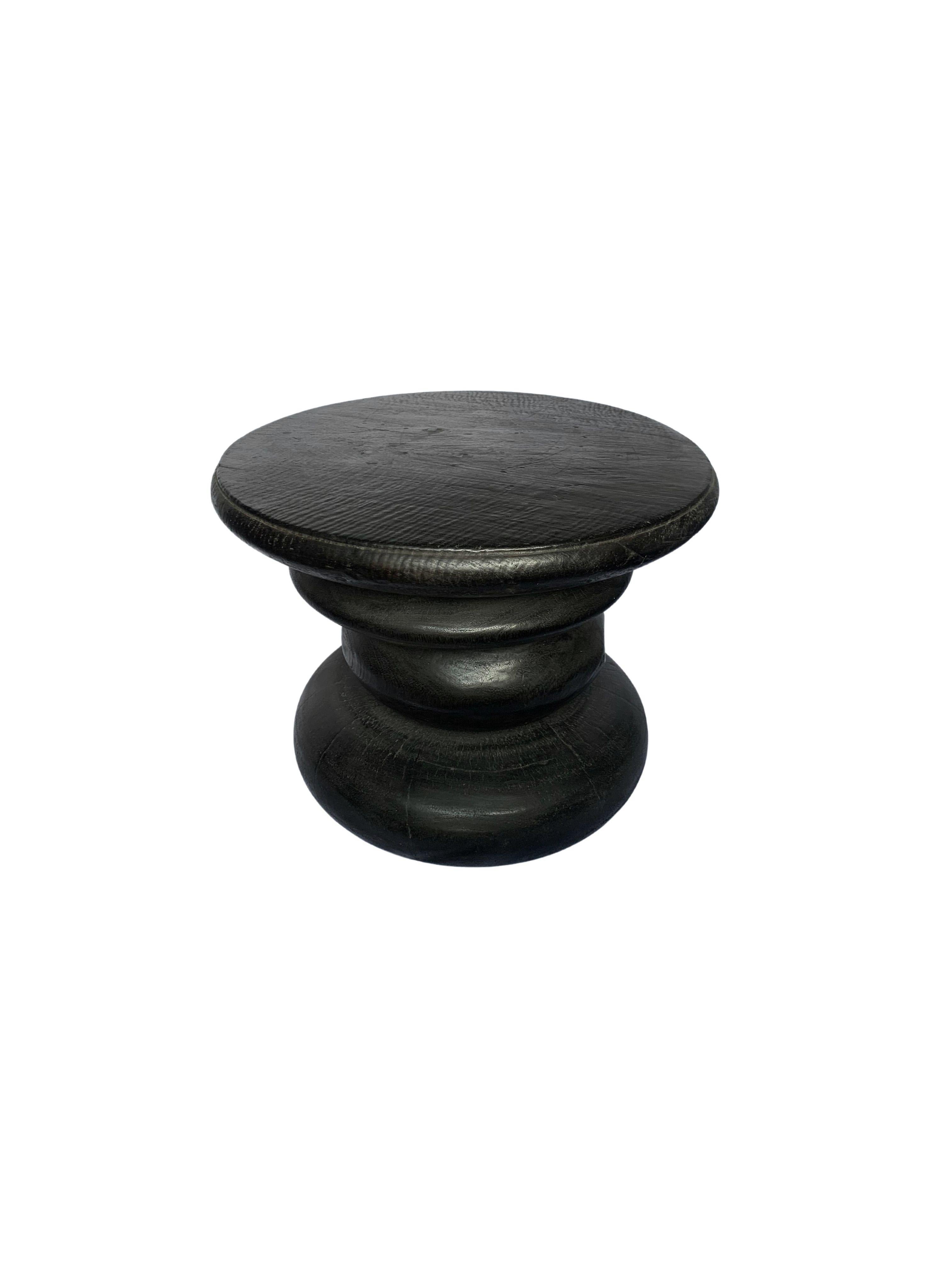 A wonderfully sculptural side table resembling a pile a river stones in a burnt finish. Its neutral pigment and subtle wood texture makes it perfect for any space. A uniquely sculptural and versatile piece certain to invoke conversation. This table