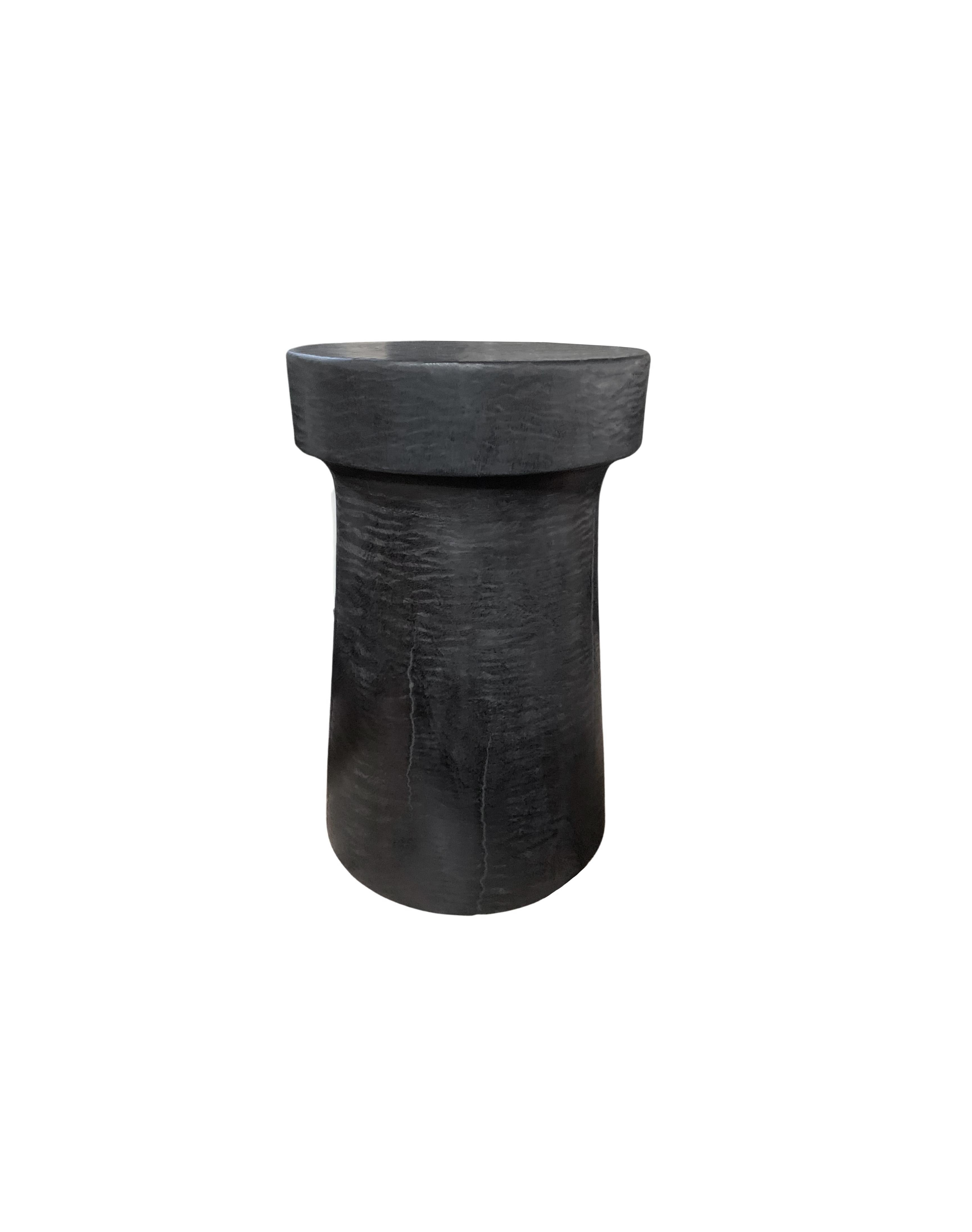 A wonderfully sculptural round side table. Its black pigment was achieved through a burning process creating both a wonderful colour and effect. Its neutral pigment and subtle wood texture makes it perfect for any space. A uniquely sculptural and