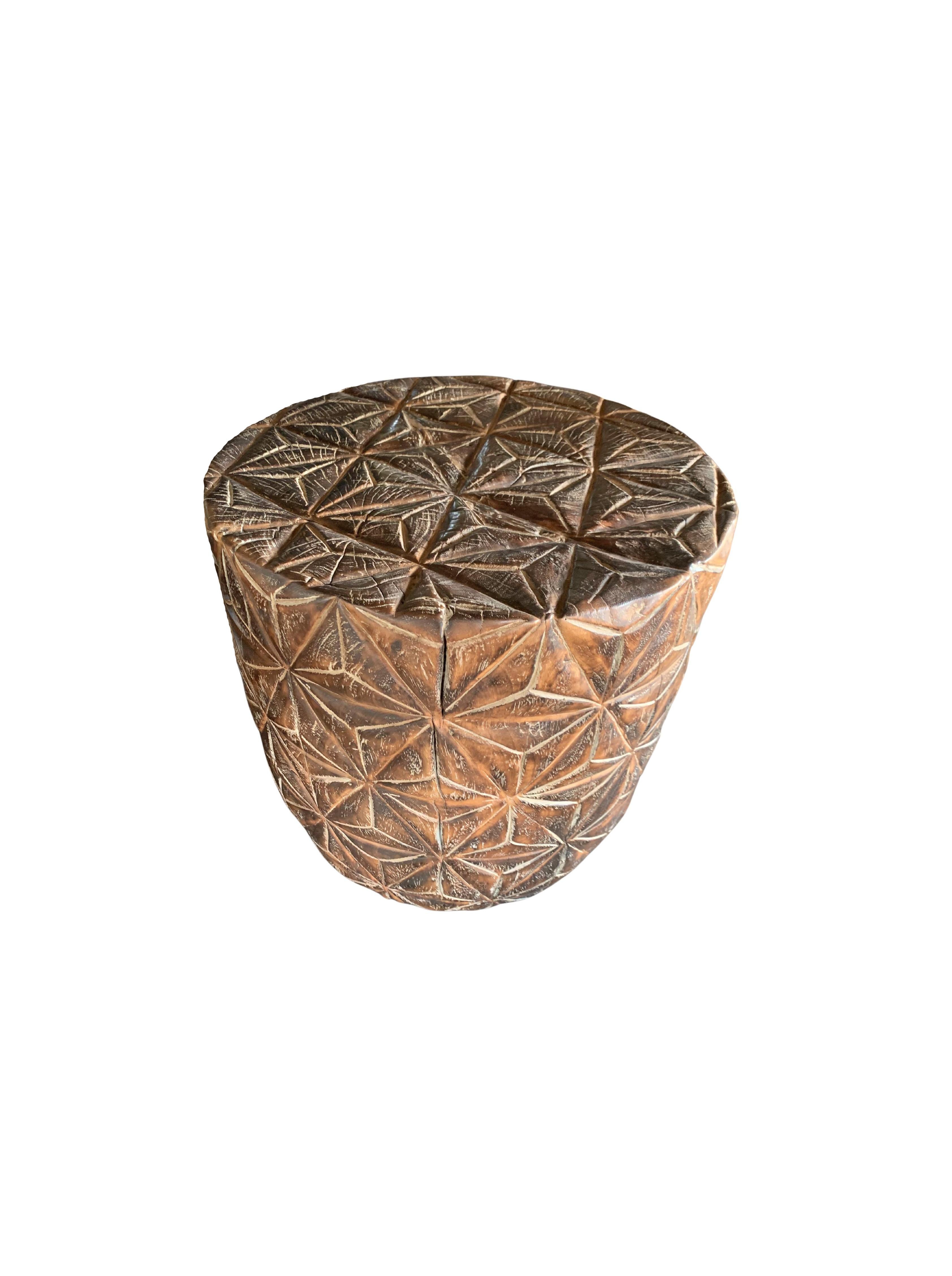 A wonderfully sculptural side table with a geometric pattern hand-carved on all sides. Its neutral pigment and subtle wood texture makes it perfect for any space. A uniquely sculptural and versatile piece certain to invoke conversation. This table