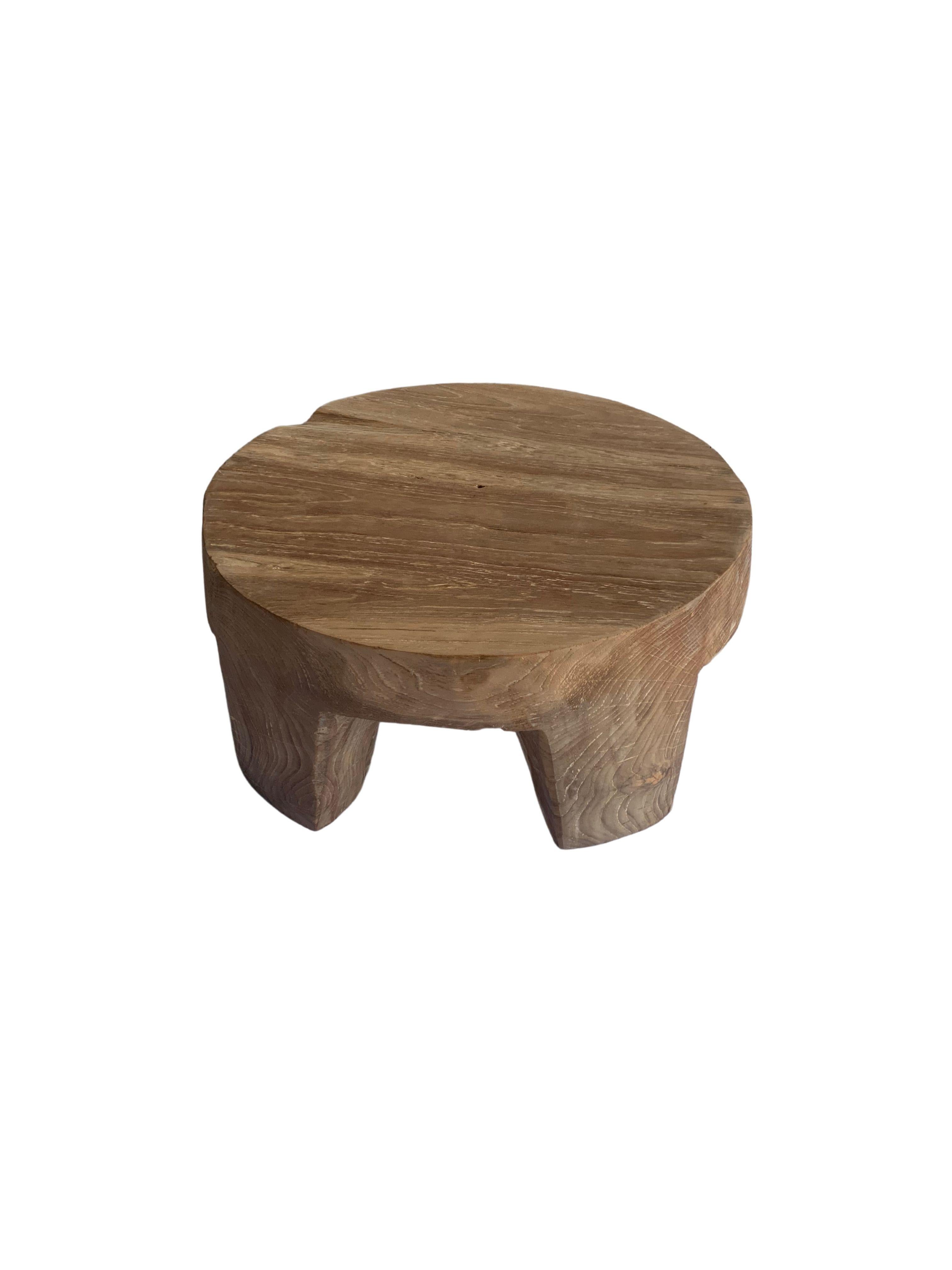 This side table was crafted from a single block of teak wood. A wonderfully sculptural round side table. Its neutral pigment and subtle wood texture makes it perfect for any space. It features four legs with angular sides. 

 