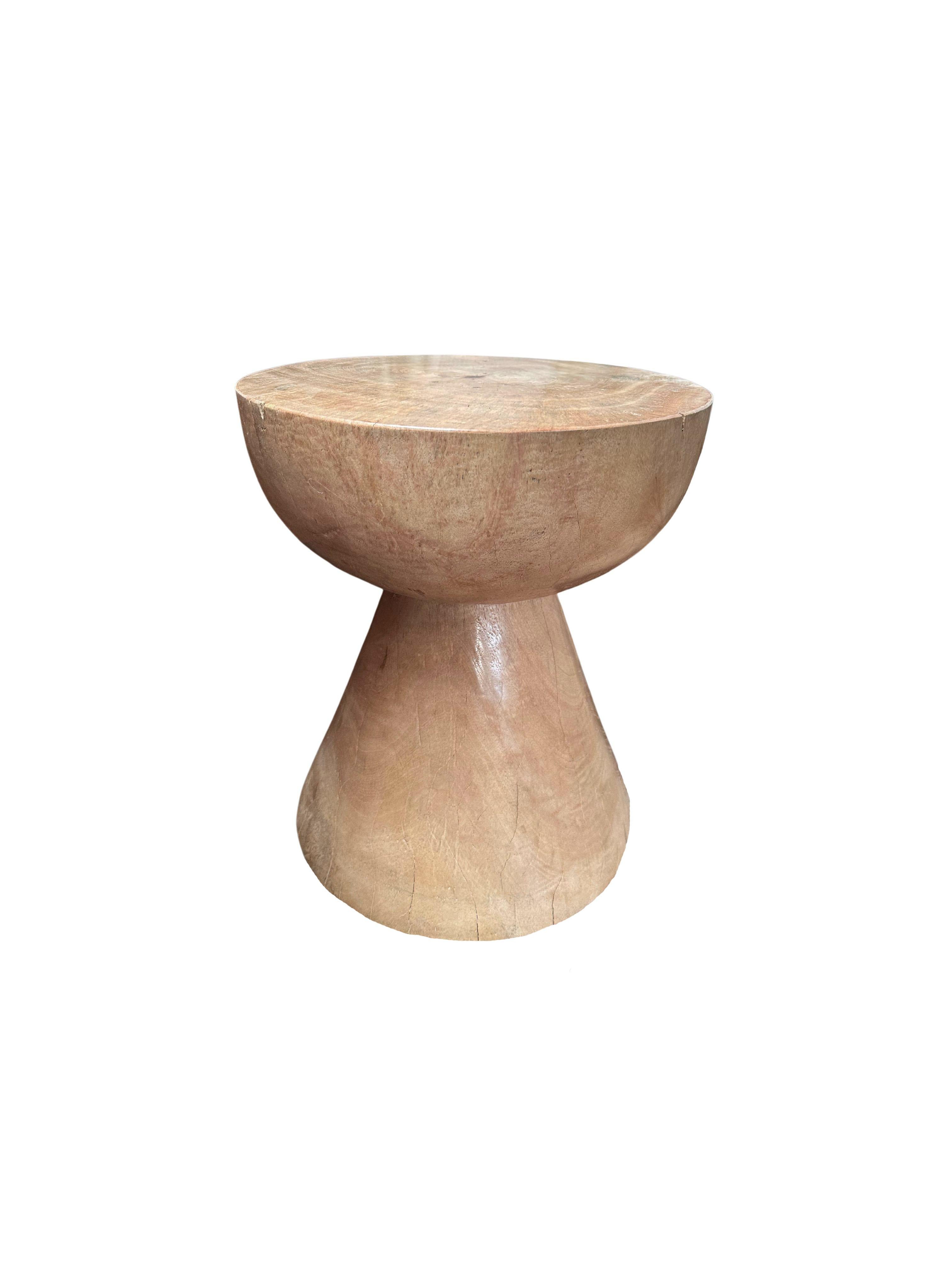 This wonderfully sculptural round side table features a bleached finish, providing a washed out tone to the wood. The table's neutral pigment makes it perfect for any space. It was crafted from a solid block of mango wood and has elegant mix of wood