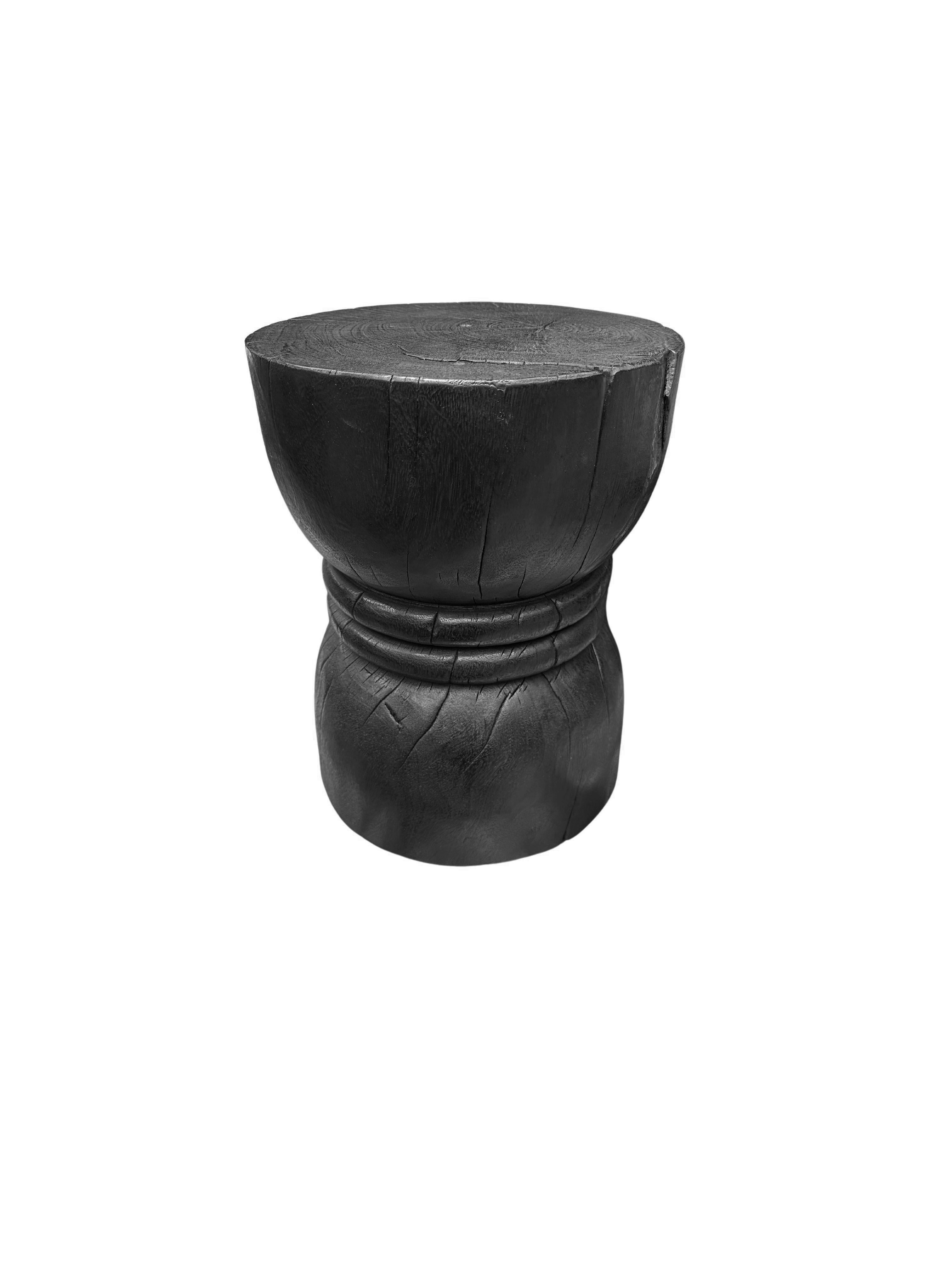 Cette table d'appoint ronde merveilleusement sculpturale est dotée d'une finition brûlée, qui donne au bois une teinte noire très prononcée. L'extérieur a été brûlé à de nombreuses reprises et recouvert d'une couche de vernis. Le pigment neutre de