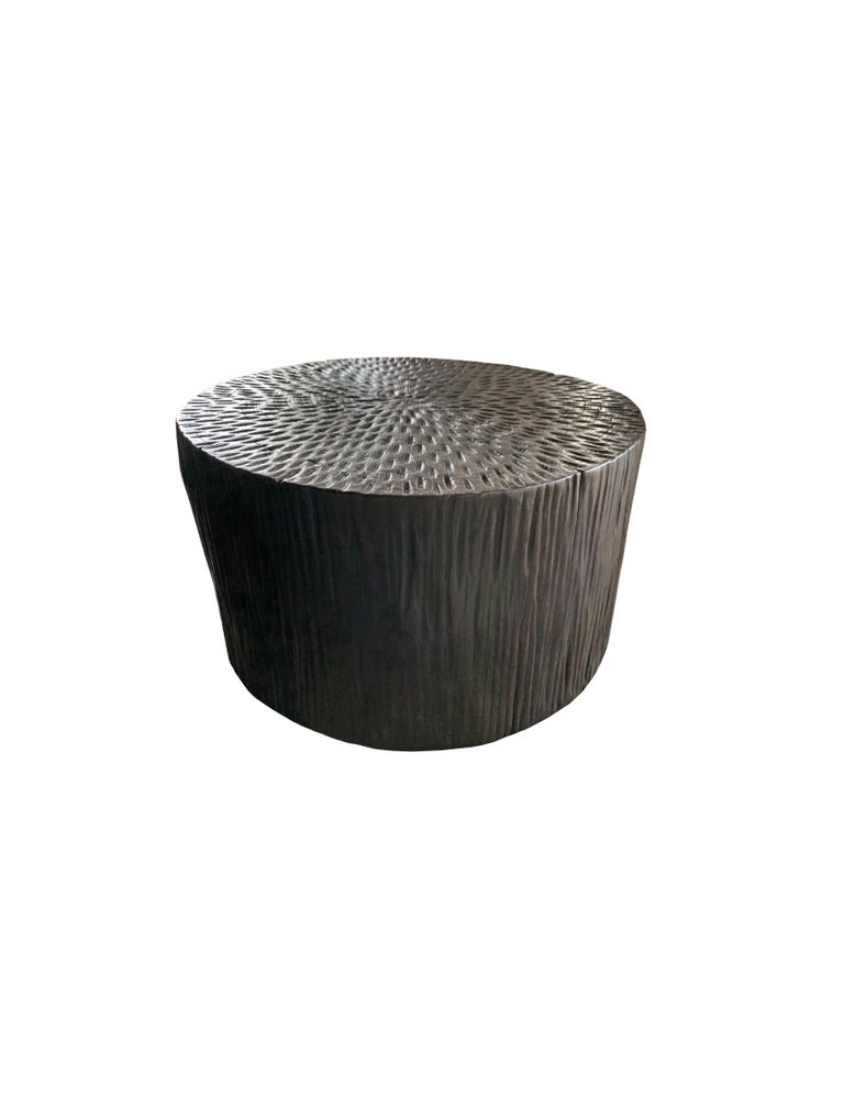 A wonderfully sculptural round side table with a hand-hewn design on its exterior. Its neutral pigment and subtle wood texture makes it perfect for any space. A uniquely sculptural and versatile piece certain to invoke conversation. This table was