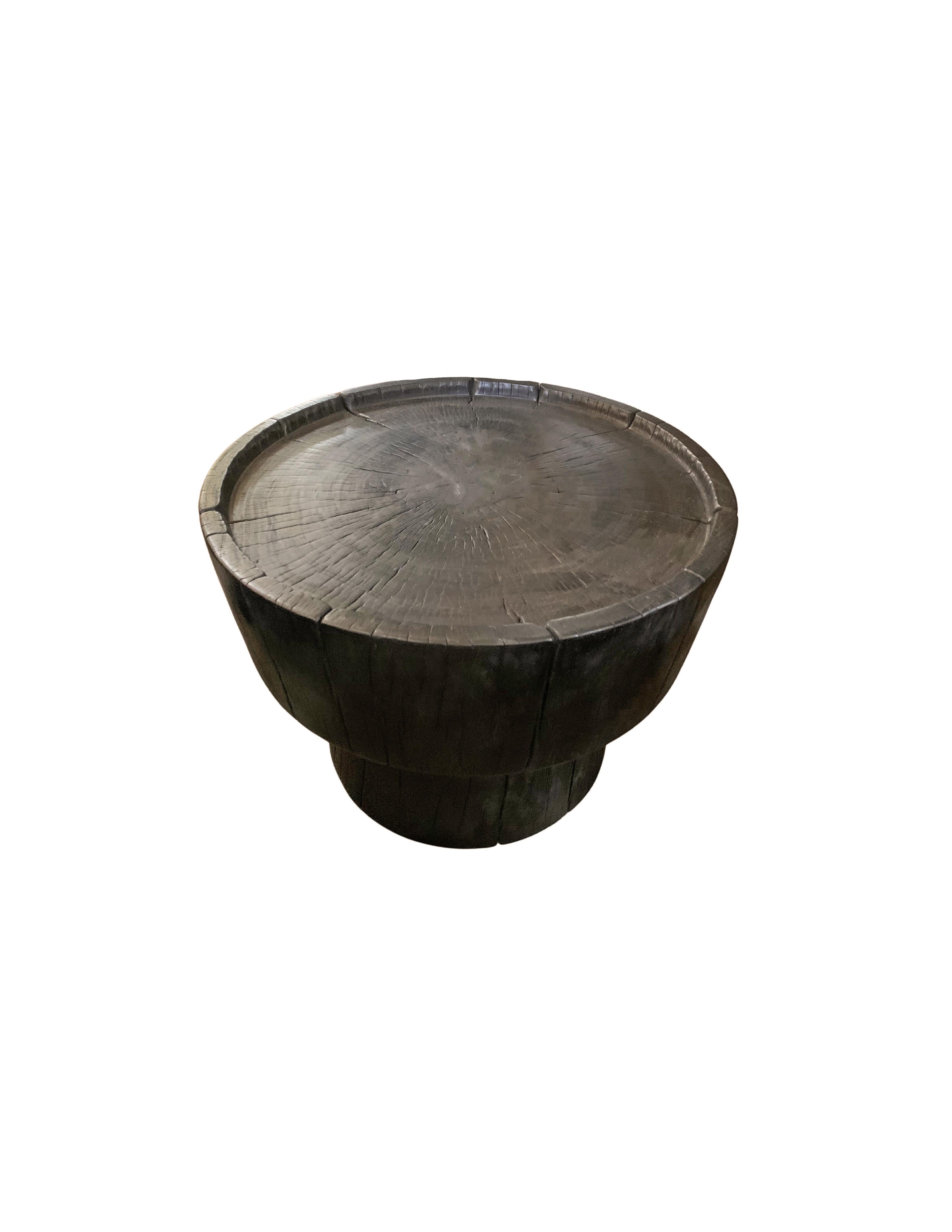 A wonderfully sculptural round side table. Its rich black pigment was achieved through burning the wood three times. Its neutral pigment and subtle wood texture makes it perfect for any space. A uniquely sculptural and versatile piece certain to