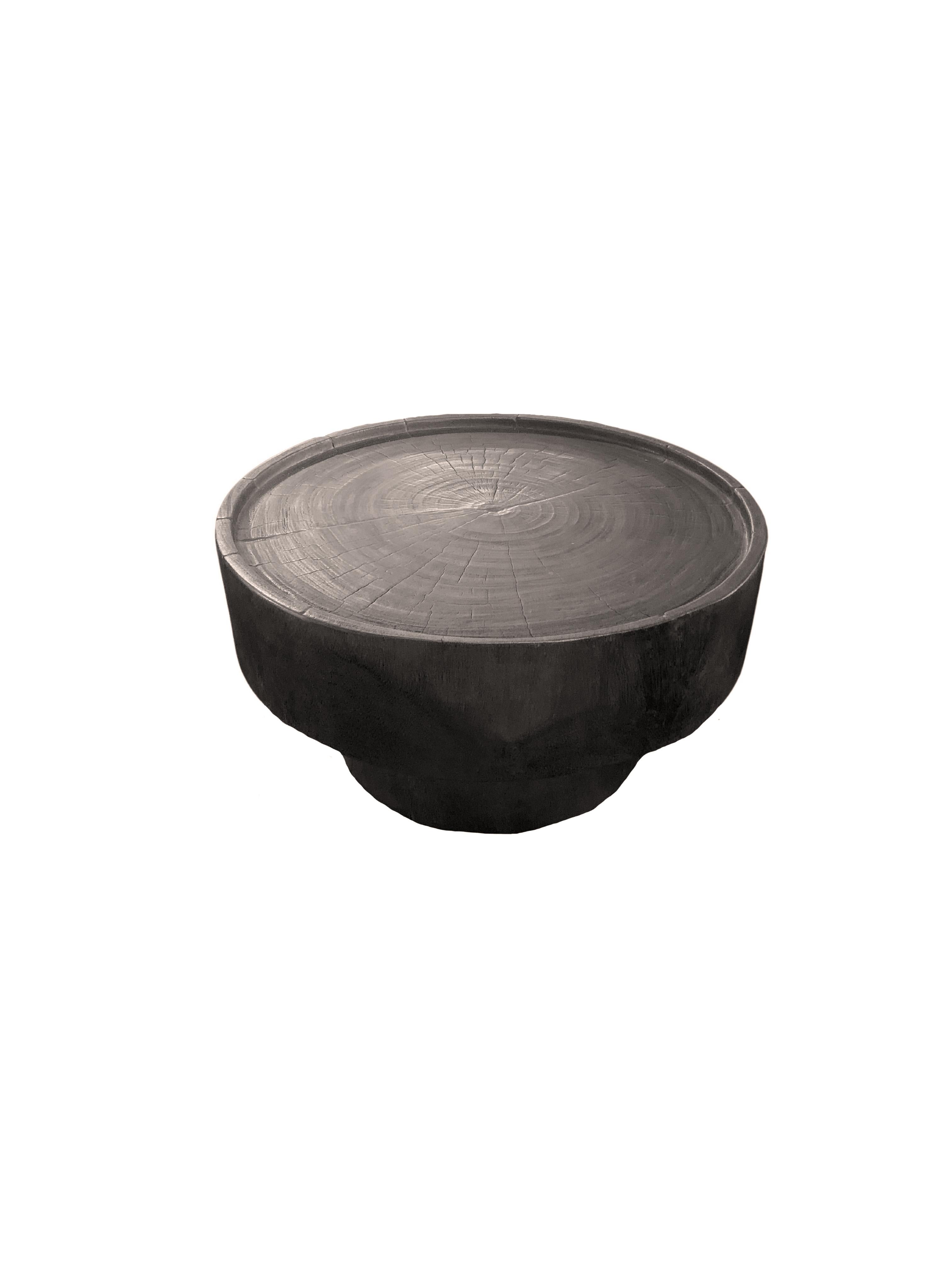 A wonderfully sculptural round side table. Its rich black pigment was achieved through burning the wood three times. Its neutral pigment and subtle wood texture makes it perfect for any space. A uniquely sculptural and versatile piece certain to