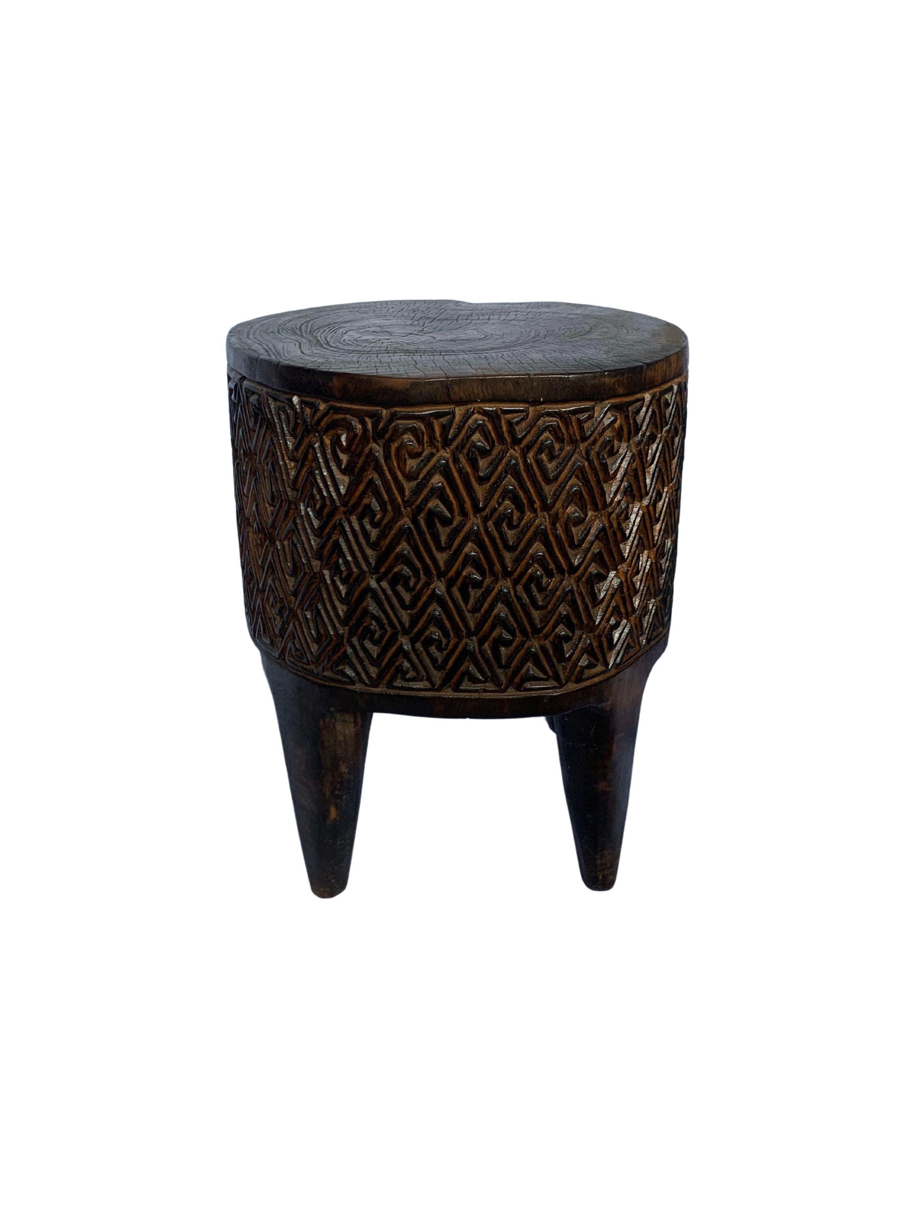 A wonderfully sculptural round side table with a wonderful hand-carved design on its exterior. Its neutral pigment and subtle wood texture makes it perfect for any space. A uniquely sculptural and versatile piece certain to invoke conversation. This