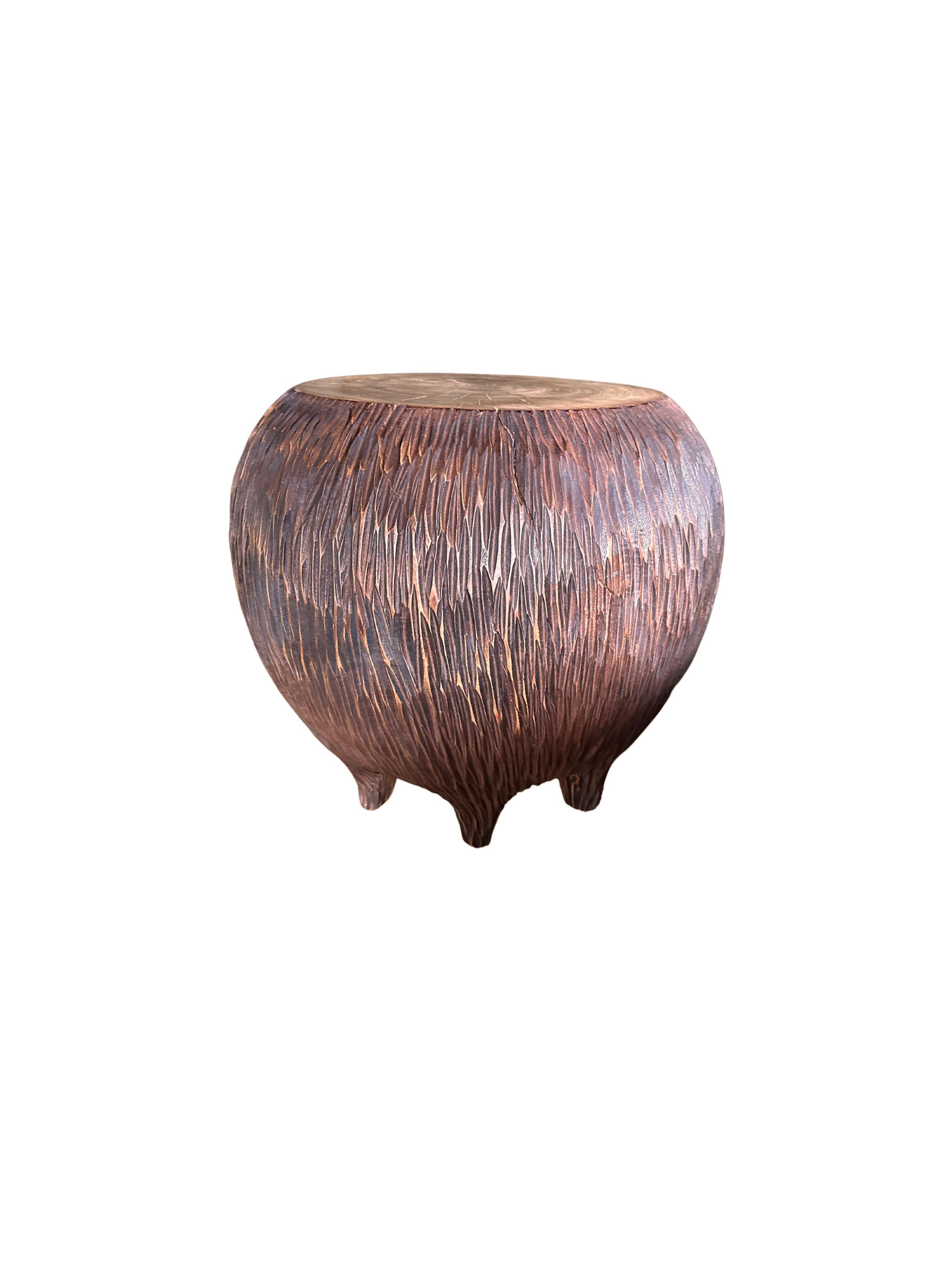 An elegantly rounded, sculptural side table crafted from a single block of mango wood. This table is elevated by 6 shallow legs that blend with the overall form. Unique to this table is the hand-hewn detailing on all sides. The table top was sanded