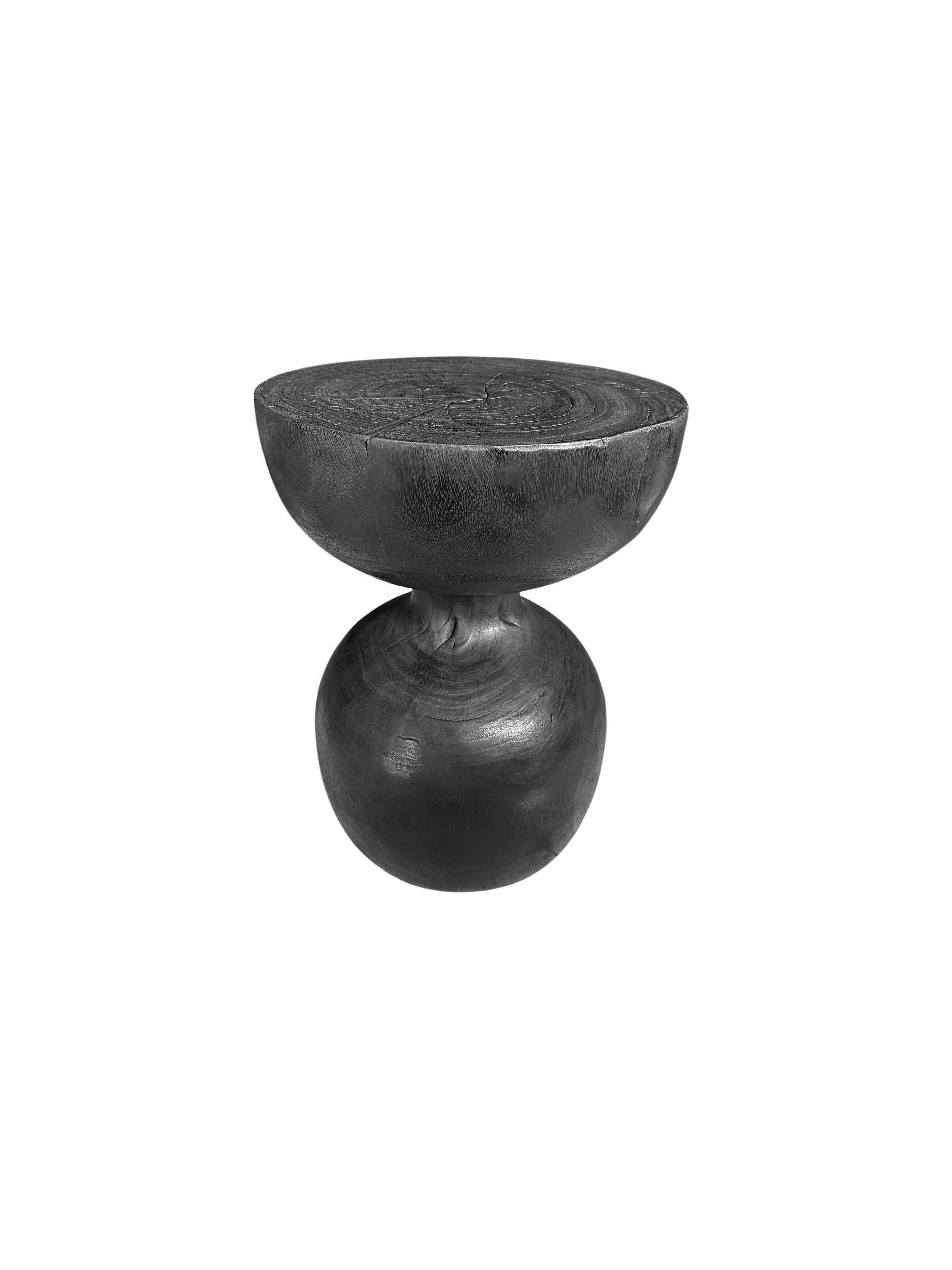 Une table d'appoint ronde merveilleusement sculpturale. Son pigment et sa texture ont été obtenus grâce à une finition brûlée où le bois a été brûlé plusieurs fois et terminé par une couche transparente. Une pièce unique, sculpturale et polyvalente.