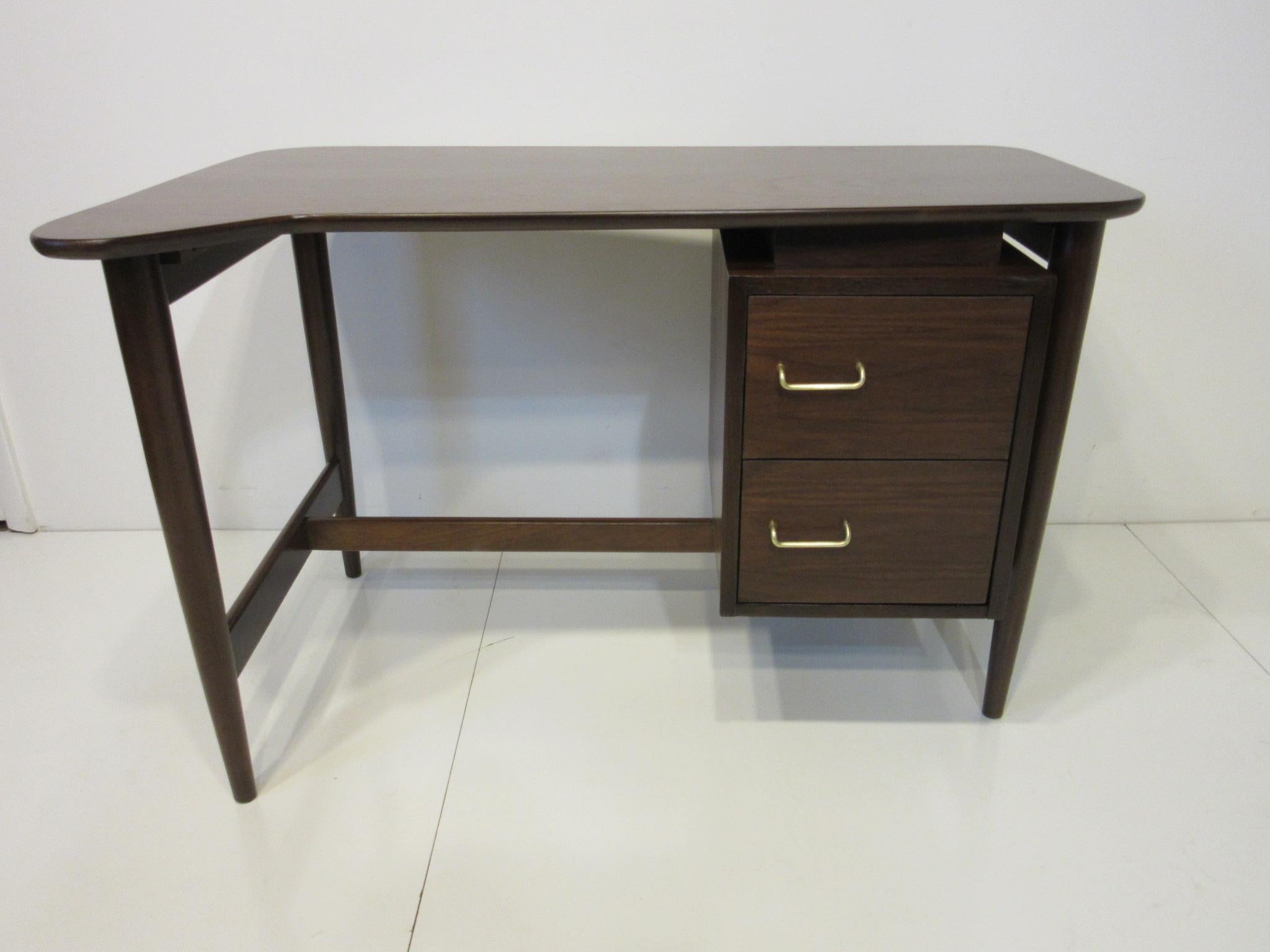 A nice smaller sized walnut desk with a sculptural styled top having two drawers with brass handles, the desk has a wonderful feel for a smaller space. Manufactured by the American of Martinsville Furniture Company, the measurement for the desk top