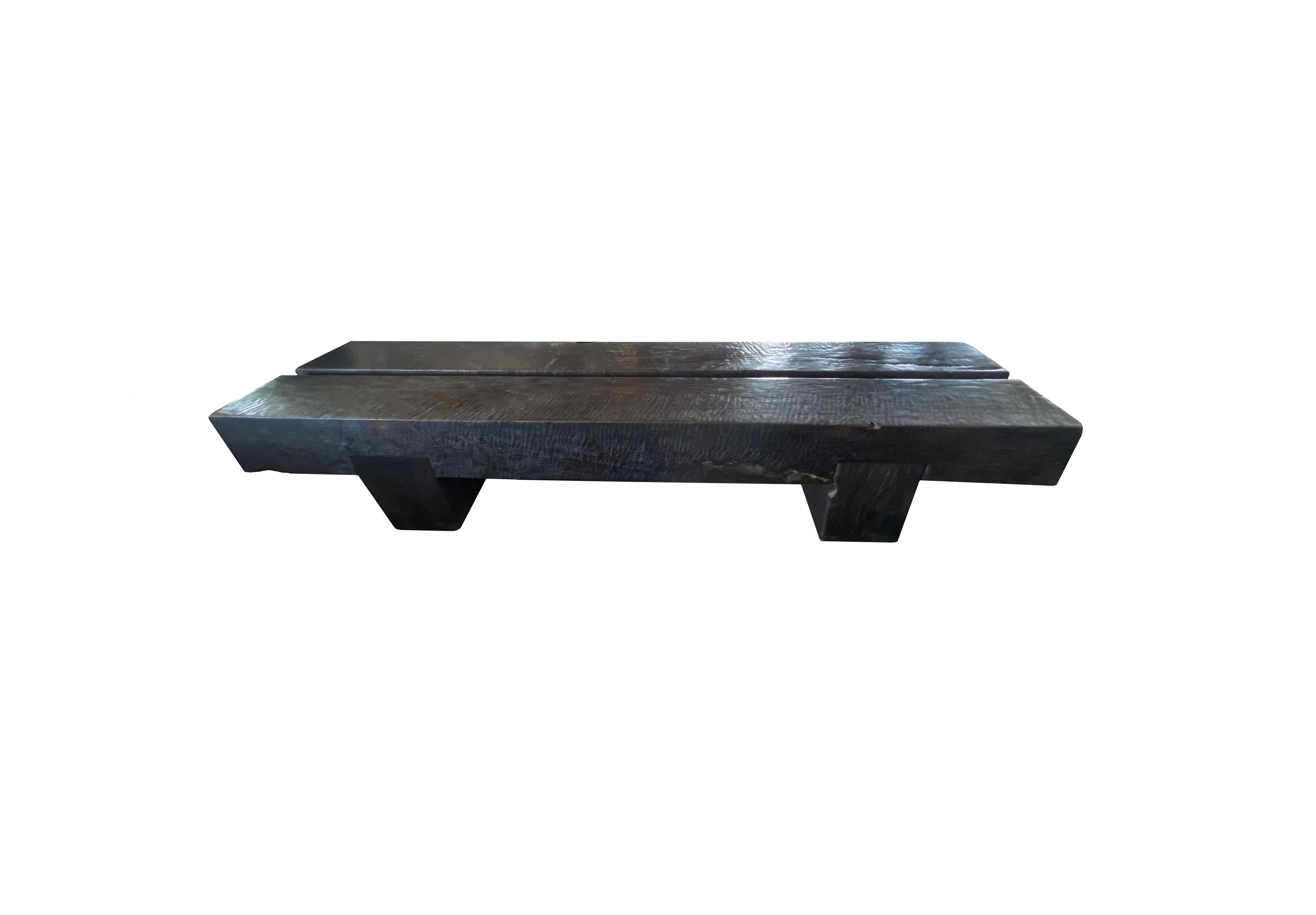 A sculptural solid mango wood bench. To achieve is rich black pigment the bench was burnt three times and then finished with a clear coat. The myriad of textures make for a very elegant bench. A wonderful addition to any space.  It features a