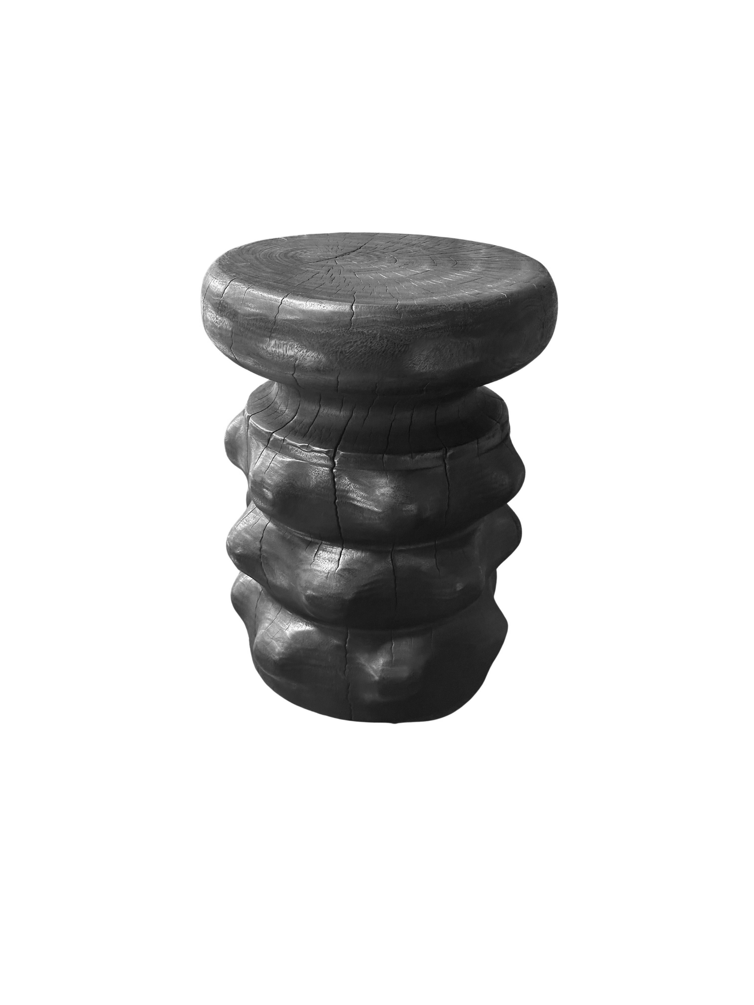 This elegant black round side table features a unique burnt finish that enhances its striking aesthetic. The rich, dark hue is beautifully contrasted by the intricate carved detailing along the sides, which showcases skillful craftsmanship and adds