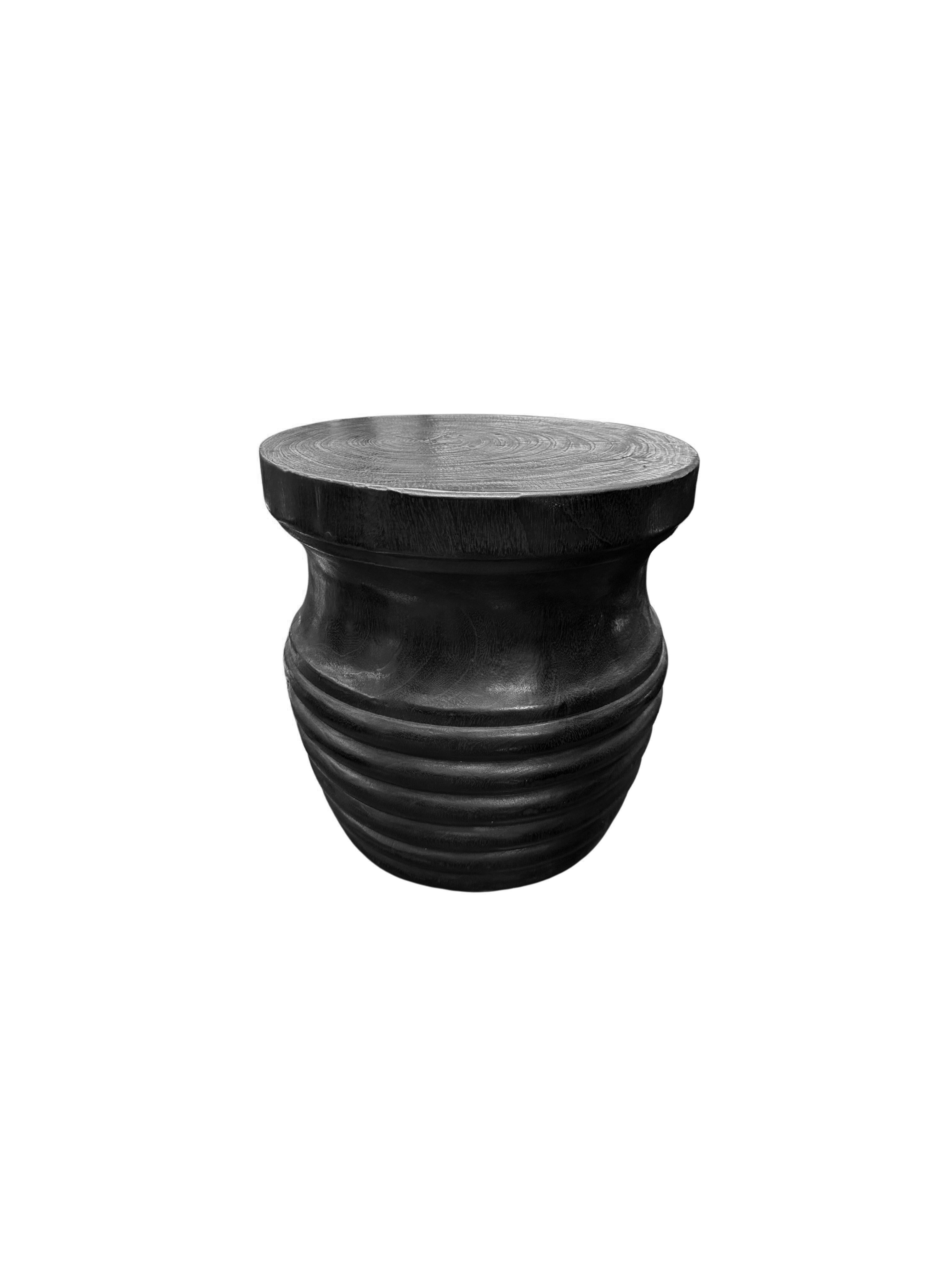 This elegant black round side table features a unique burnt finish that enhances its striking aesthetic. The rich, dark hue is beautifully contrasted by the intricate carved detailing along the sides, which showcases skillful craftsmanship and adds