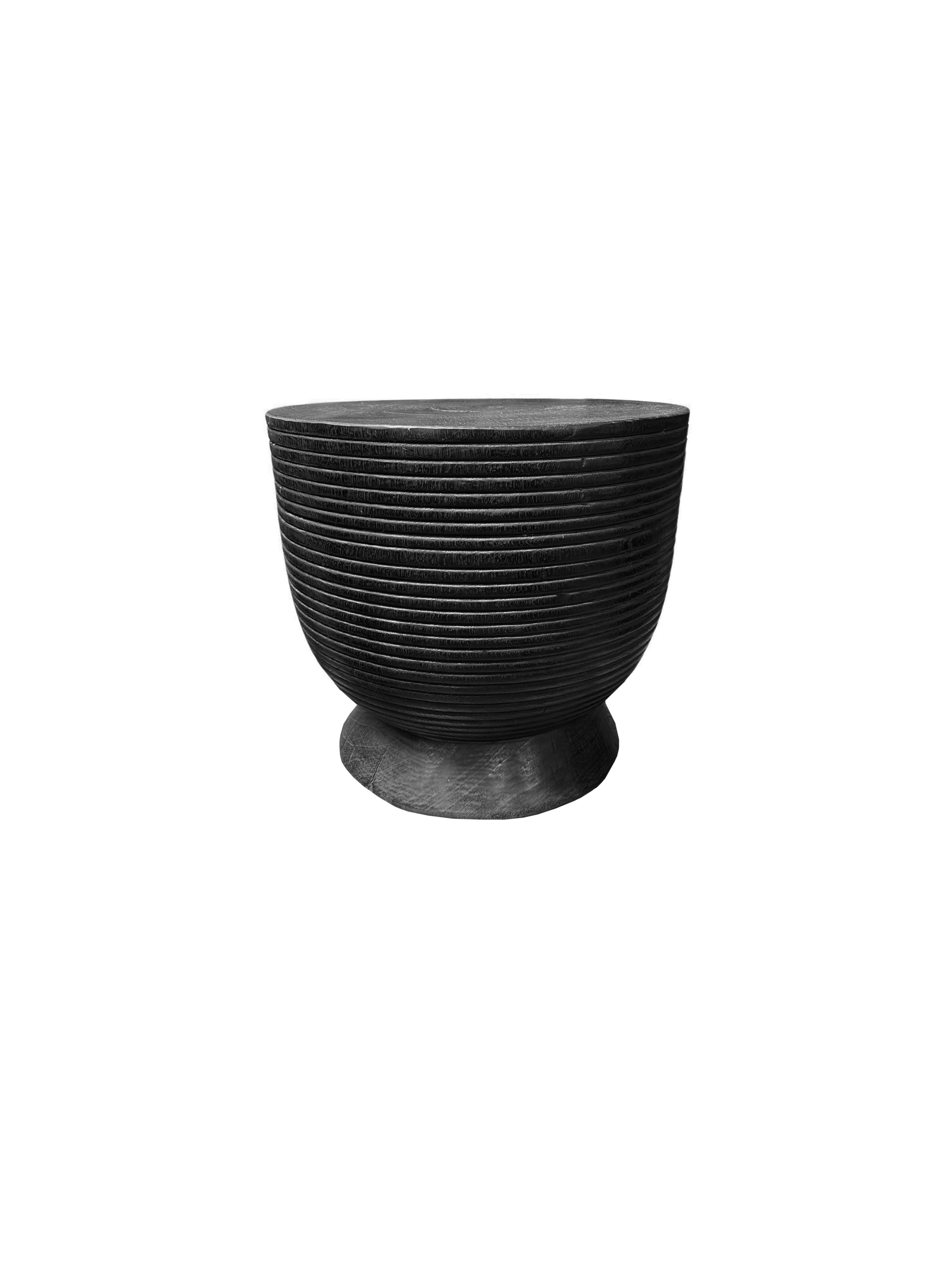 This elegant black round side table features a unique burnt finish that enhances its striking aesthetic. The rich, dark hue is beautifully contrasted by the intricate carved detailing along the sides, which showcases skillful craftsmanship and adds