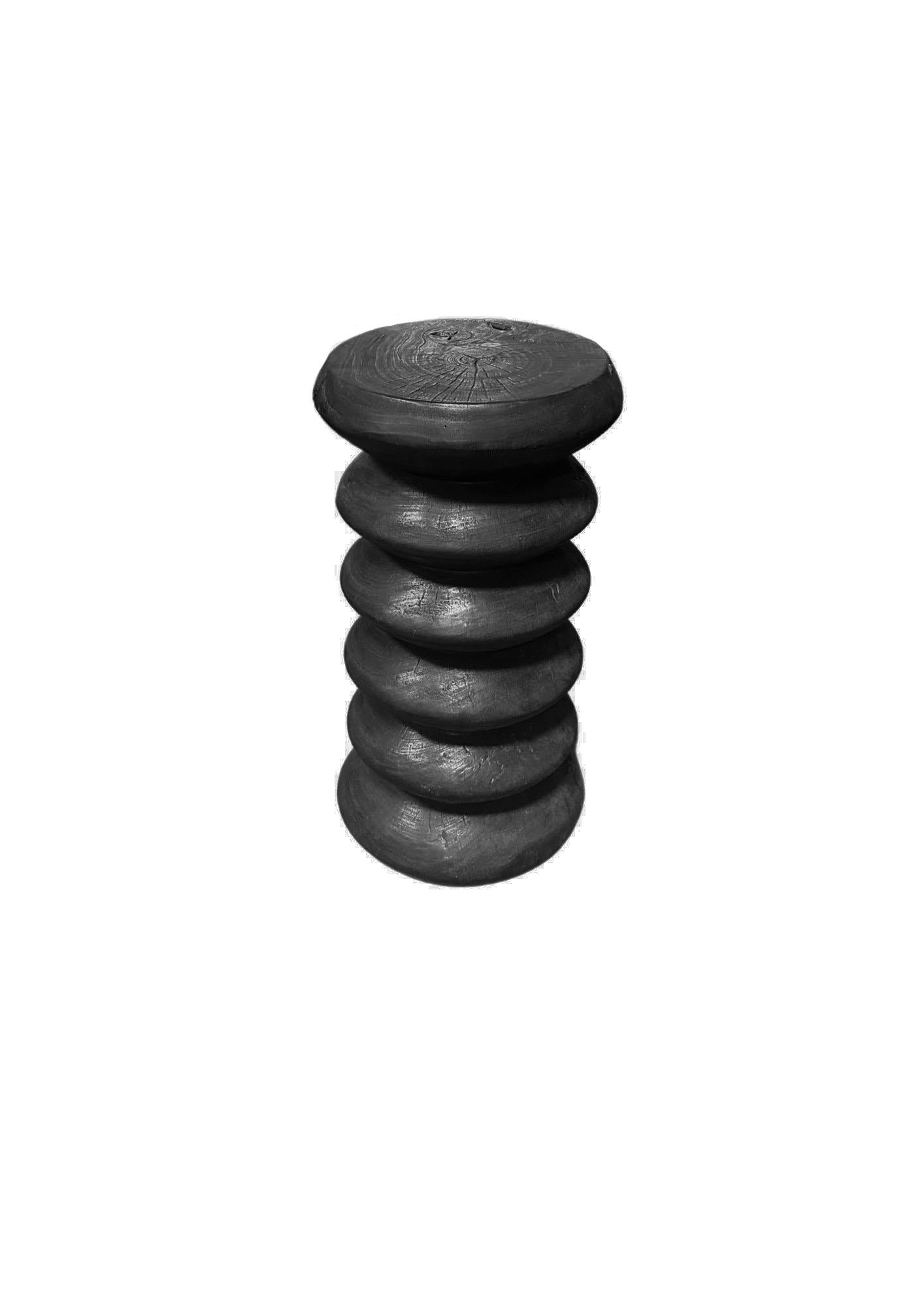 Fabriquée en bois de manguier massif, cette table d'appoint remarquable présente une finition noire brûlée audacieuse qui met en valeur son grain naturel et ses riches textures. Son design empilé unique crée une silhouette sculpturale, mêlant l'art