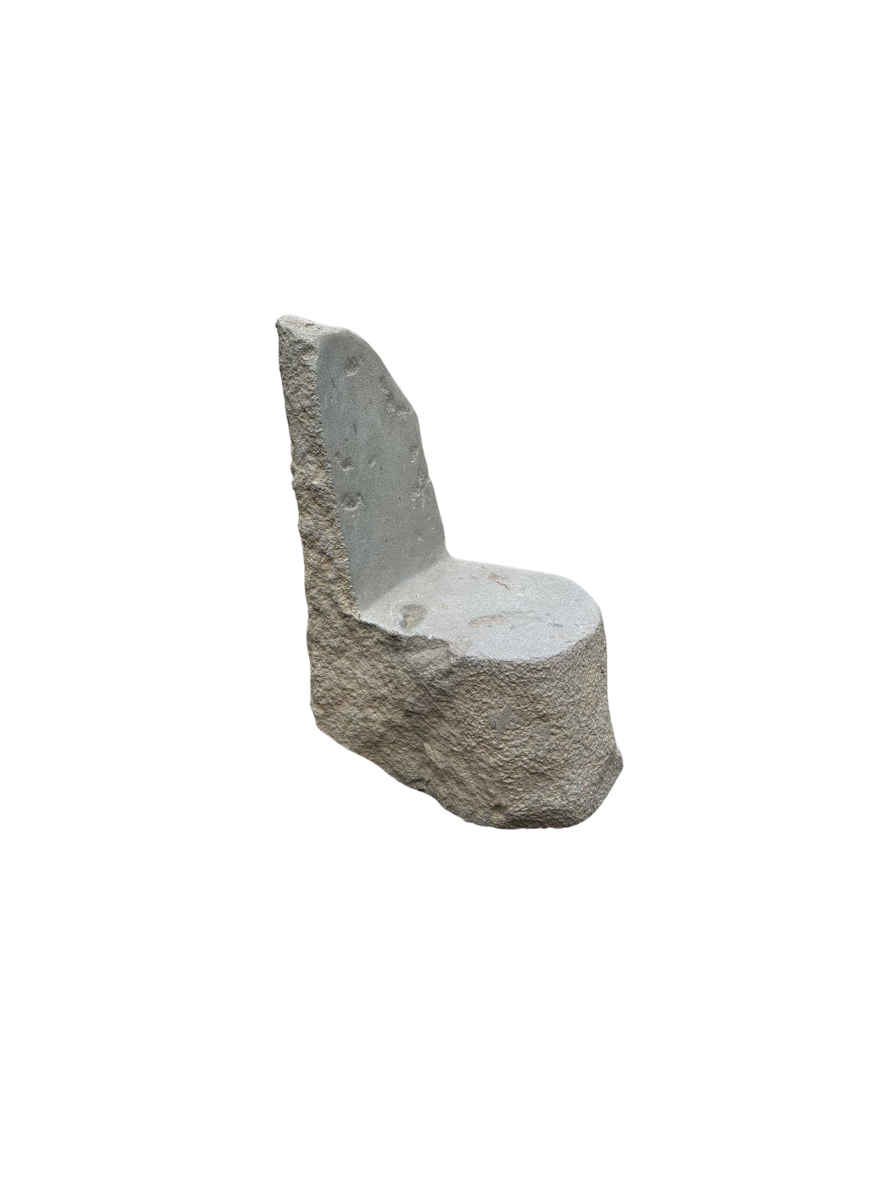 Une chaise en pierre incroyablement lourde et solide. Ce bel objet sculptural a été fabriqué à partir d'une pierre massive provenant du lit d'une rivière de l'est de Java. Un objet brut et organique avec de belles textures. Le mélange des teintes