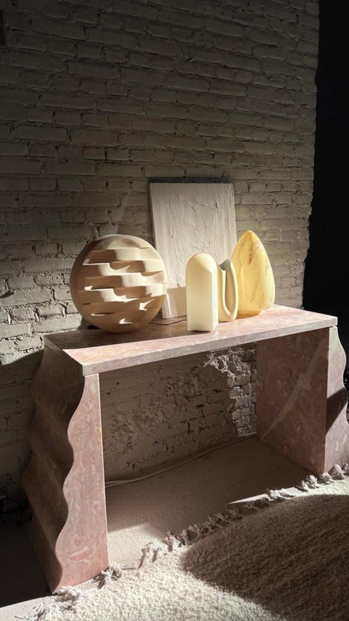 Two wave-shaped stone feet are the feature of this multipurpose console/desk. 

This sculptural piece has a perfect eye for proportion abed form and colour. The piece fits well in contemporary interiors inspired by art, and minimalism and even in an