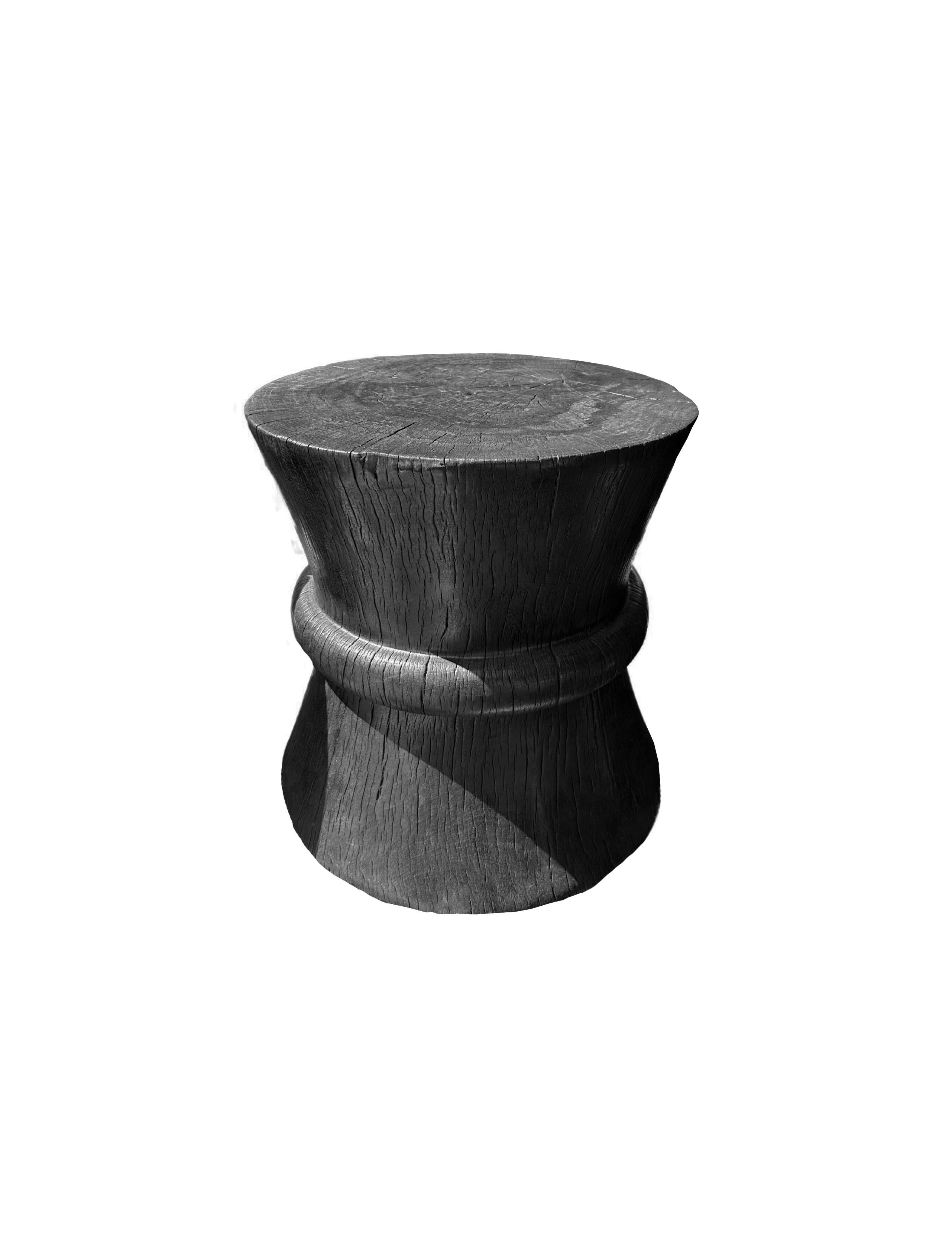 A wonderfully sculptural round side table. Its black pigment was achieved through a burning process creating both a wonderful color and effect. Its neutral pigment and wood texture makes it perfect for any space. A uniquely sculptural and versatile