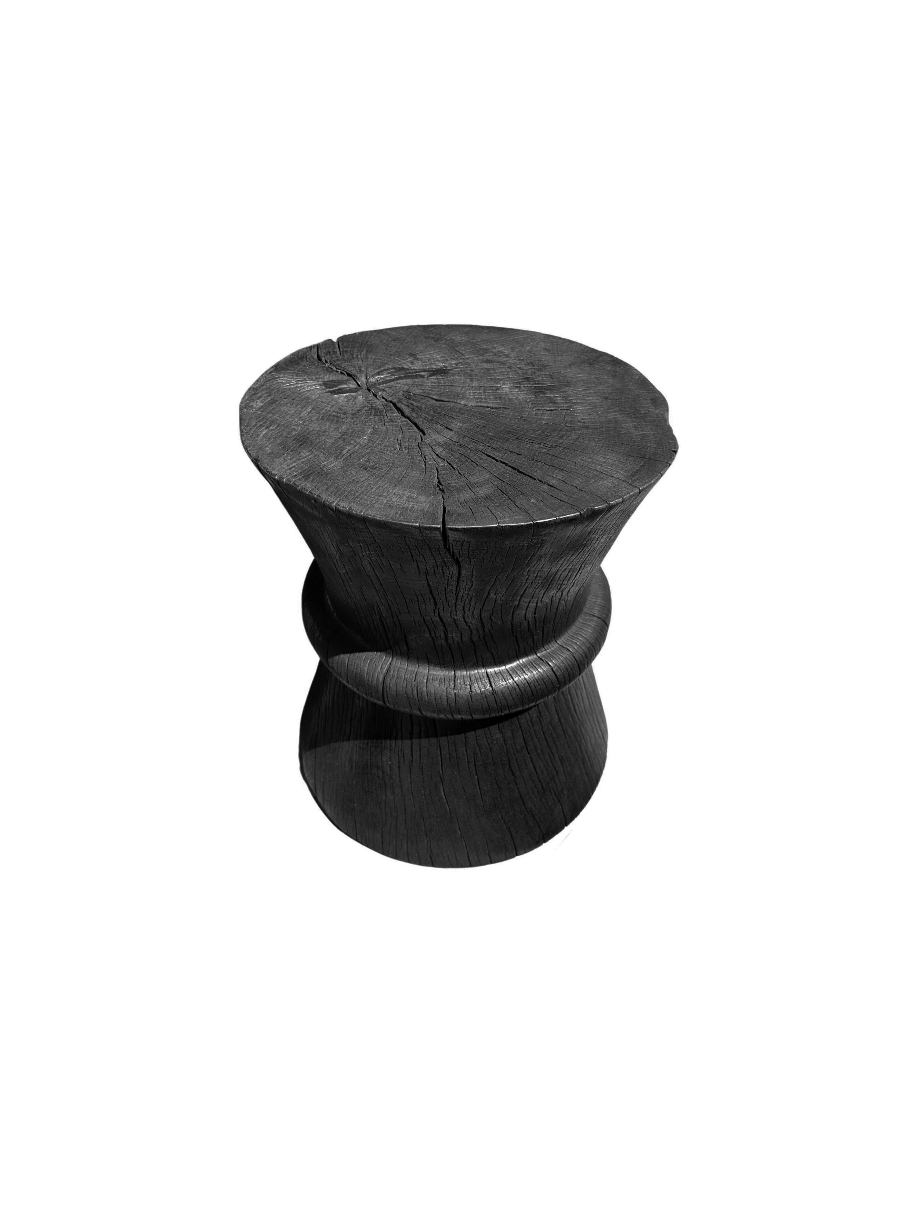A wonderfully sculptural round side table. Its black pigment was achieved through a burning process creating both a wonderful color and effect. Its neutral pigment and wood texture makes it perfect for any space. A uniquely sculptural and versatile