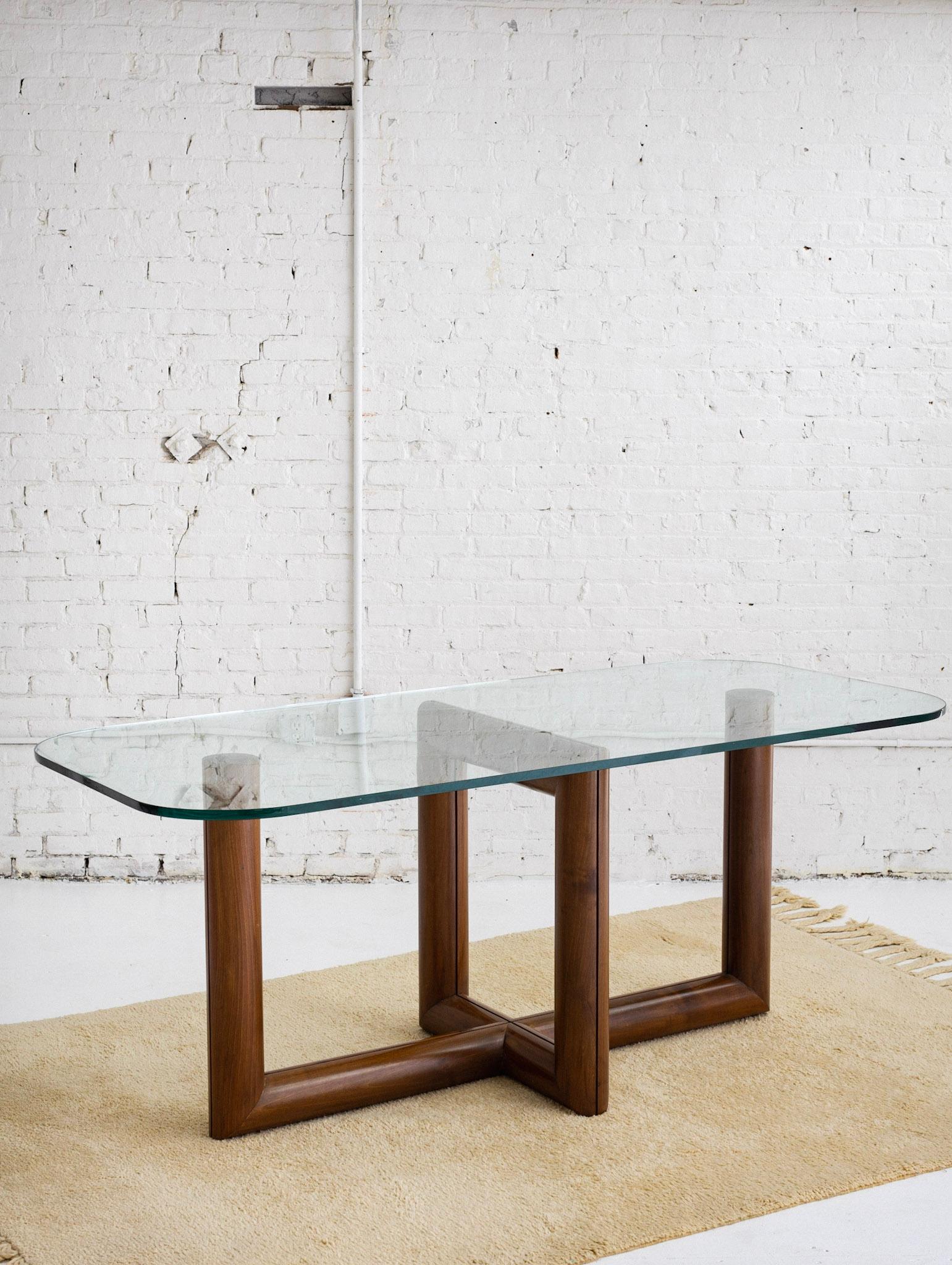An impressive glass and wood dining table sourced outside of Florence, Italy. Its original owners stated that it was designed custom for the home by the home's architect. A solid wood base. Tubular form with a sculpted architectural silhouette.