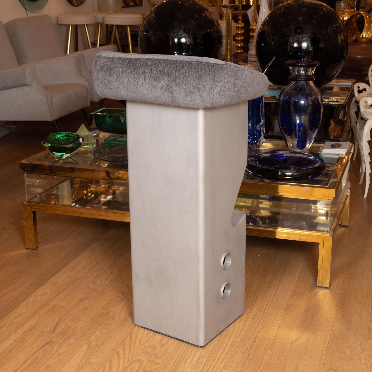 Sculptural stainless steel bar stool with upholstered seat.