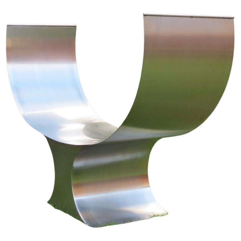 Maßgefertigte Gartenbank aus Edelstahl in skulpturaler Form.  Wunderbare Qualität.  Die Sitzfläche besteht aus einem Stück Edelstahlblech, das gefedert ist. Die Innenseite der Sitzfläche ist poliert und die Außenseite ist aus gebürstetem Stahl, was