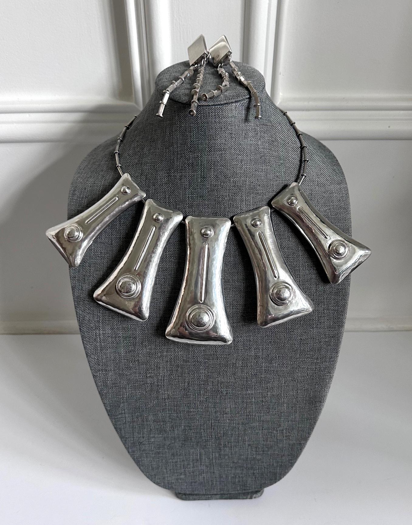 Una suite di gioielli in argento sterling dal design audace di Graziella Laffi (1923-2009), Lima, Perù, circa anni Settanta. La parure è composta da una collana a girocollo con sei grandi ciondoli geometrici cavi e da un paio di orecchini pendenti