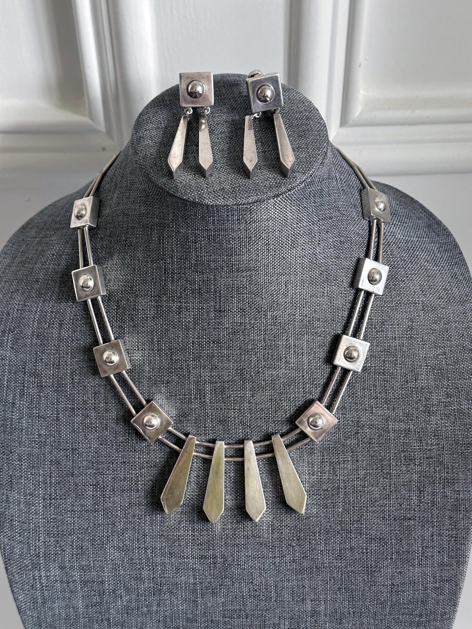 Suite de bijoux en argent sterling au design géométrique audacieux par Graziella Laffi (1923-2009), Lima, Pérou, vers les années 1970. L'ensemble se compose d'un collier à maillons présentant quatre pendentifs creux en forme de haches de tabouret en