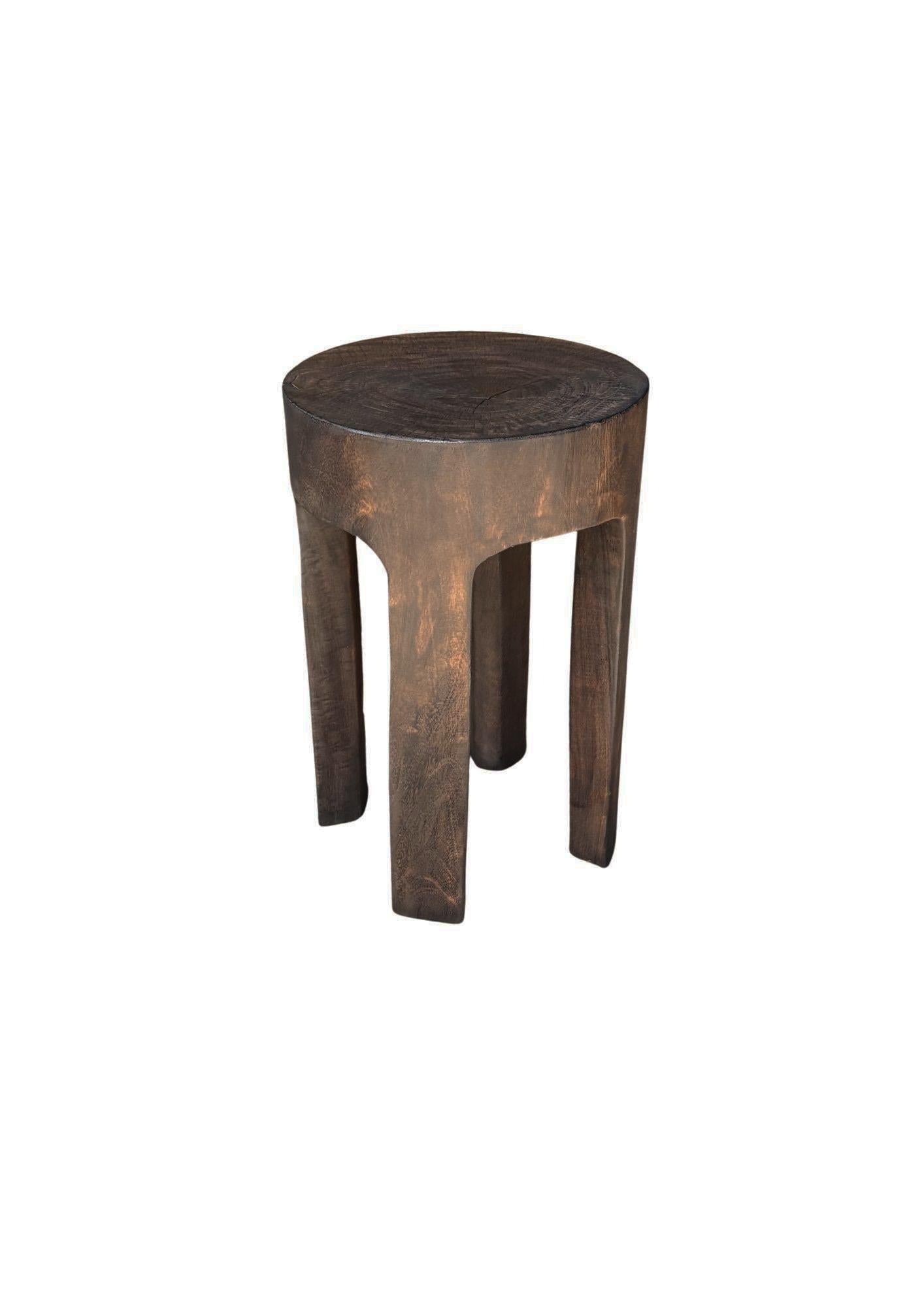 Eleva tu espacio con la discreta elegancia de este taburete de madera de mango hecho a mano. Esculpida a partir de un único bloque macizo de madera de mango de origen sostenible, presenta un rico acabado marrón oscuro espresso que realza el veteado