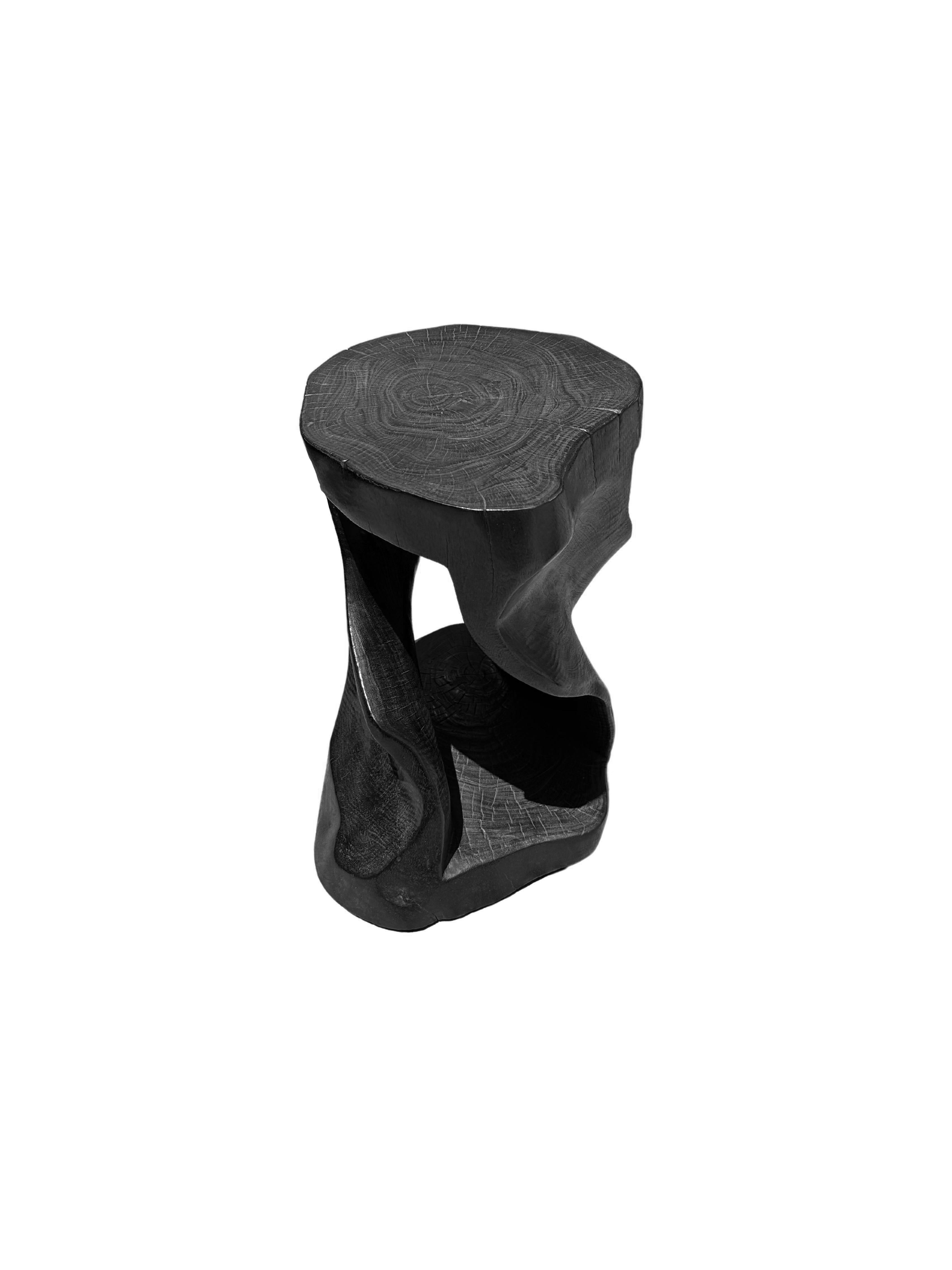 Ein wunderbar skulpturaler Hocker oder Beistelltisch, mit einer Mischung aus Holzstrukturen und -tönen. Es hat ein spiralförmiges Design mit einem freiliegenden Kern. Dieser einzigartig skulpturale und vielseitige Stuhl wurde aus einem einzigen
