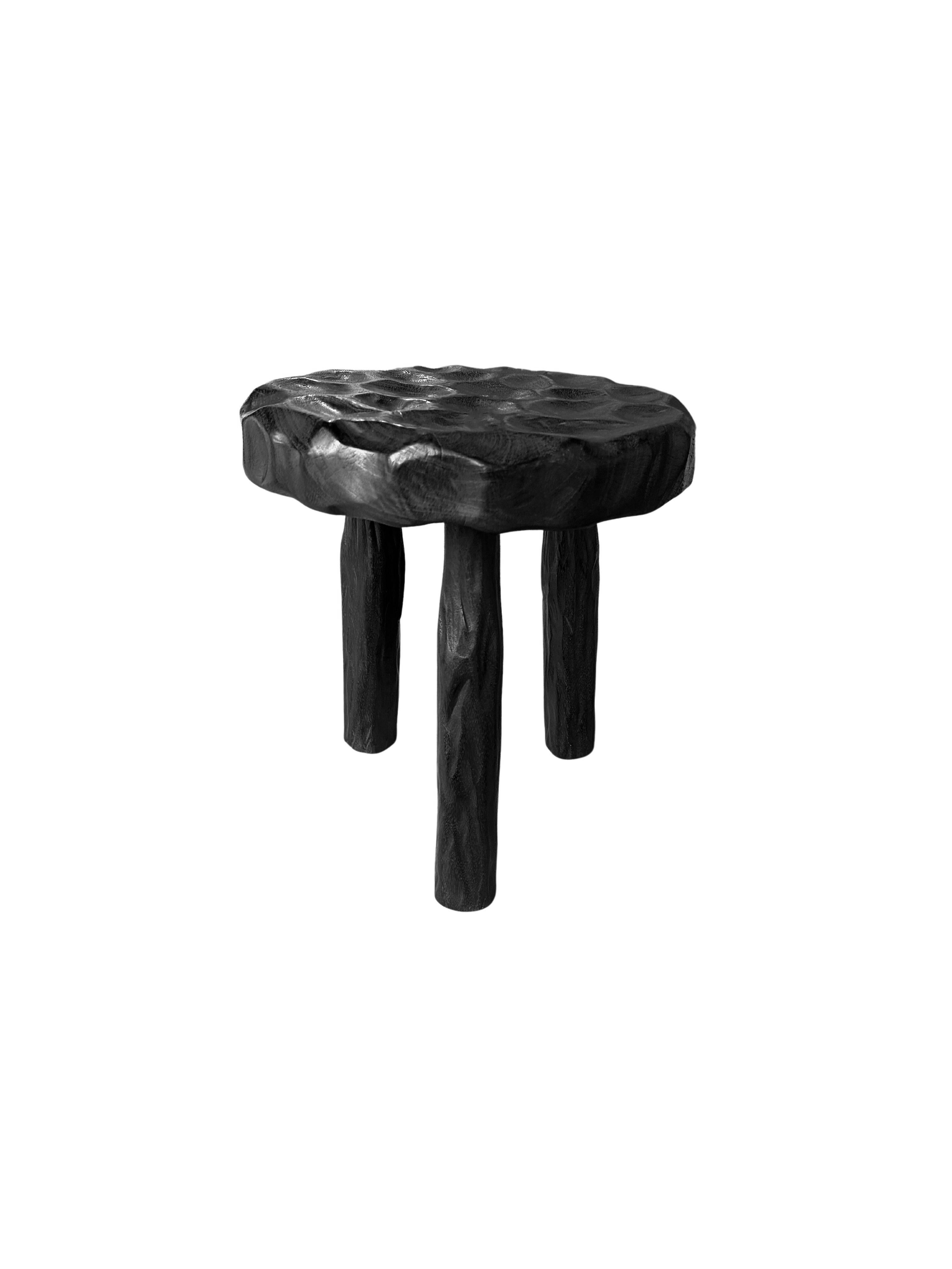 An elegantly rounded, sculptural stool crafted from mango wood. Unique to this stool is the hand-hewn detailing on all sides providing a wonderful contrast of textures. To achieve its black pigment the wood was burnt multiple times and finished with