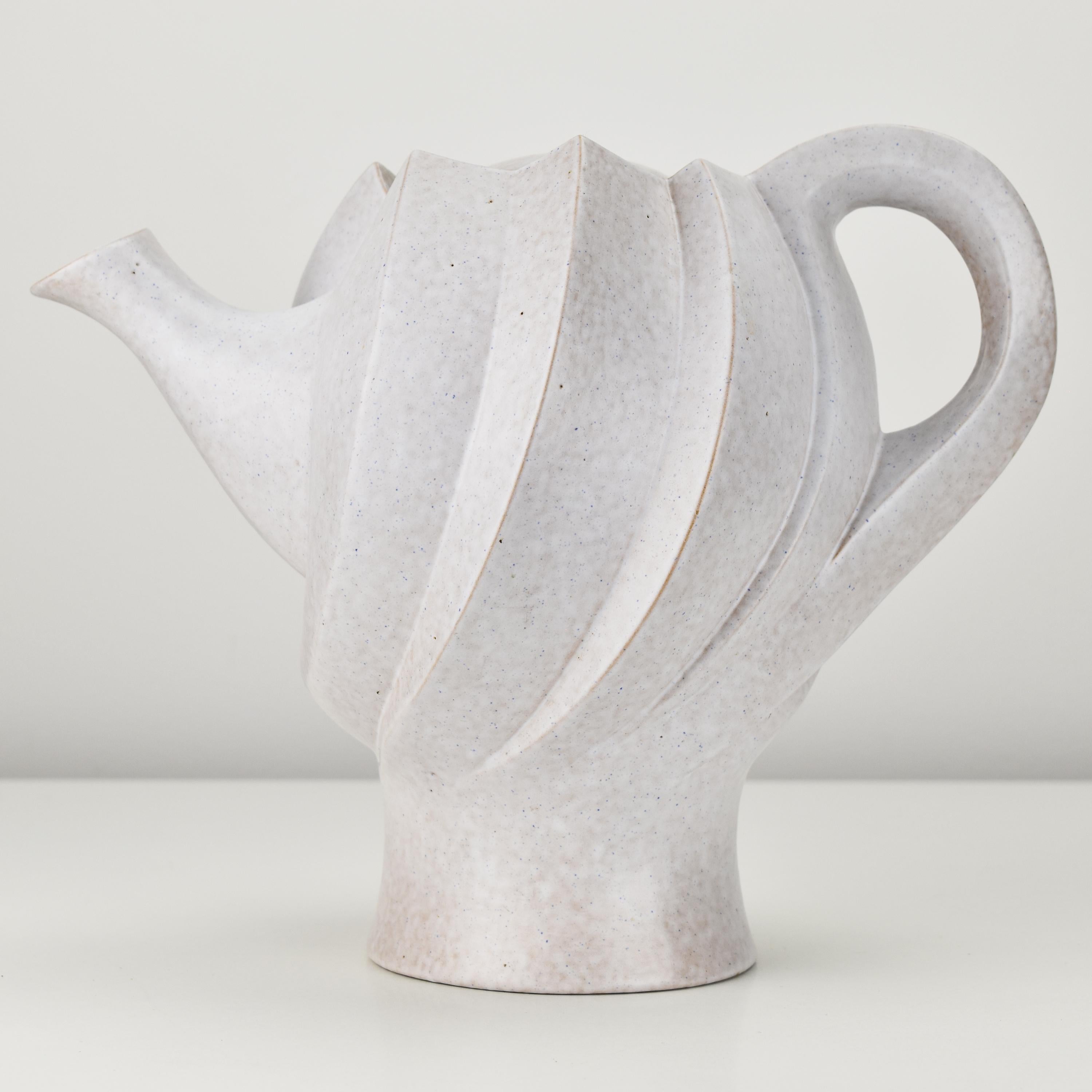 Eine ungewöhnlich skulpturale, segmentierte Teekanne und ein bemerkenswertes Stück Keramikkunst, das durch sein einzigartiges Design und seinen künstlerischen Ausdruck besticht. Die aus beige glasierter Keramik gefertigte Teekanne strahlt einen