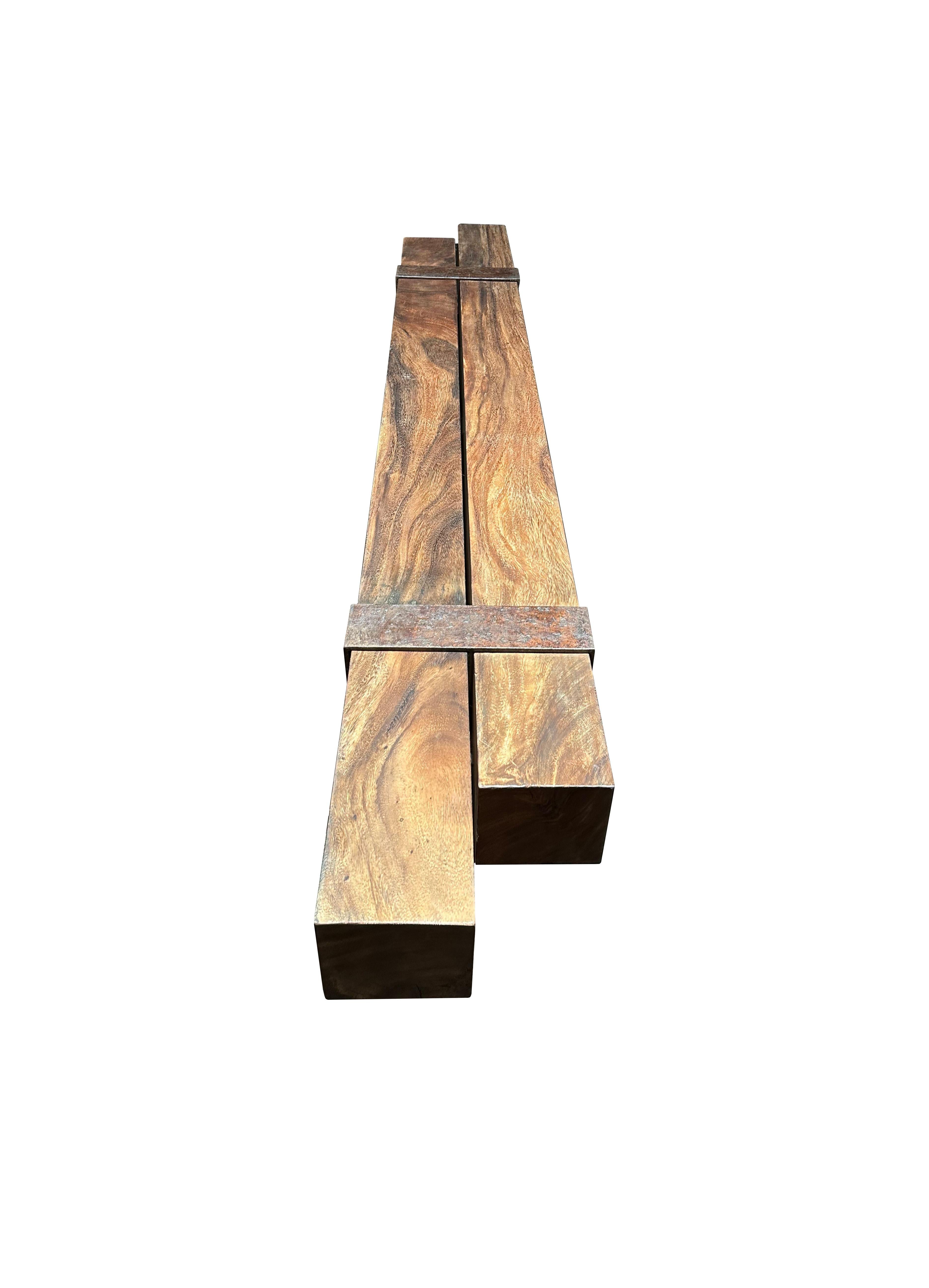 Eine skulpturale Bank aus Suar-Holz, gefertigt aus 2 massiven Suar-Balken, die voneinander abgesetzt sind und von 2 industriellen Stahlbeinen getragen werden. Diese Bank hat eine wunderbare Mischung aus Holztexturen und -tönen. Das perfekte Objekt,
