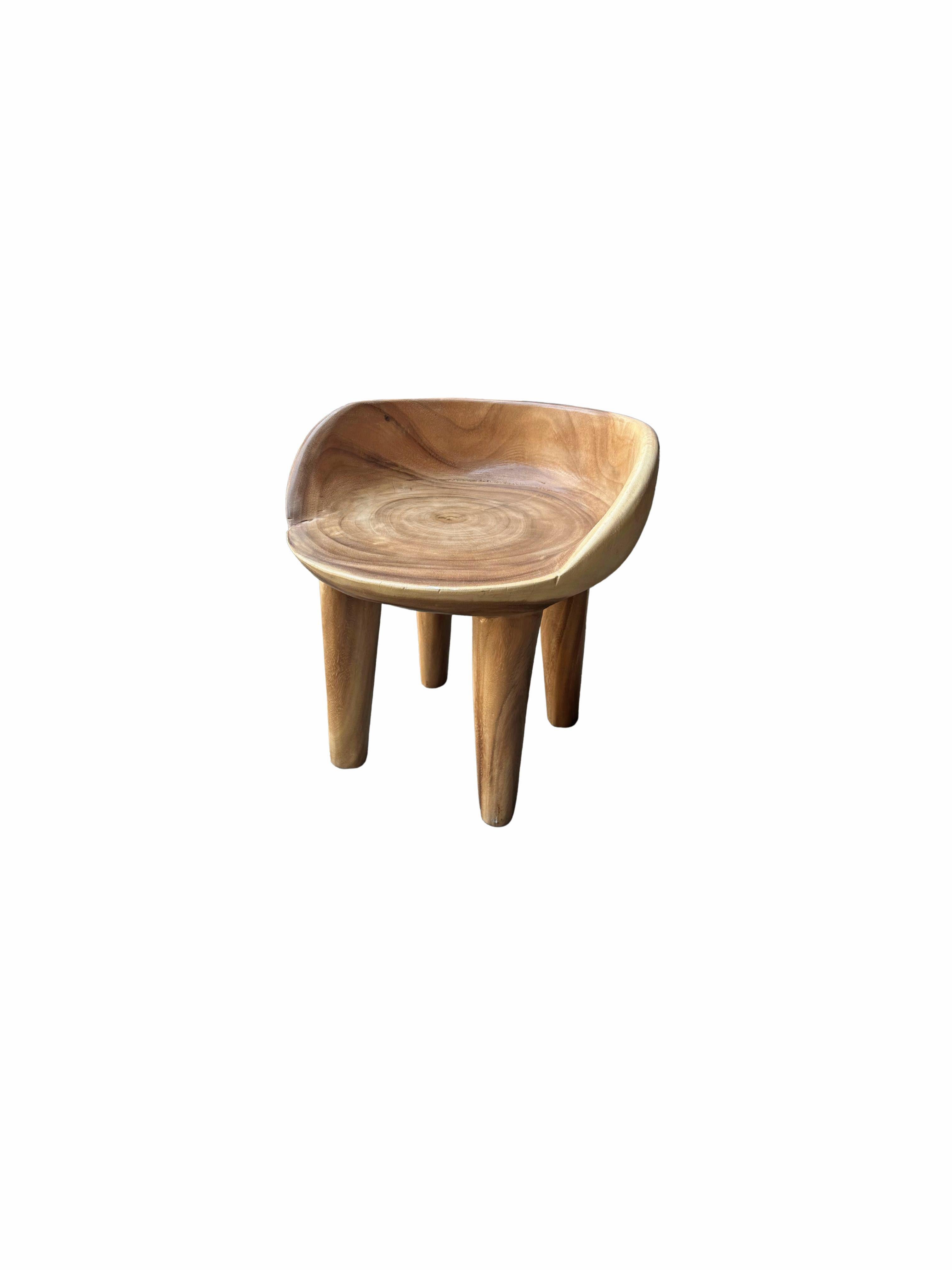 This wonderfully sculptural chair was crafted from a single block of suar wood. The chair sits on 4 slender legs. Its neutral pigment makes it perfect for any space. This chair features a natural finish with a clear coat. It was sanded down