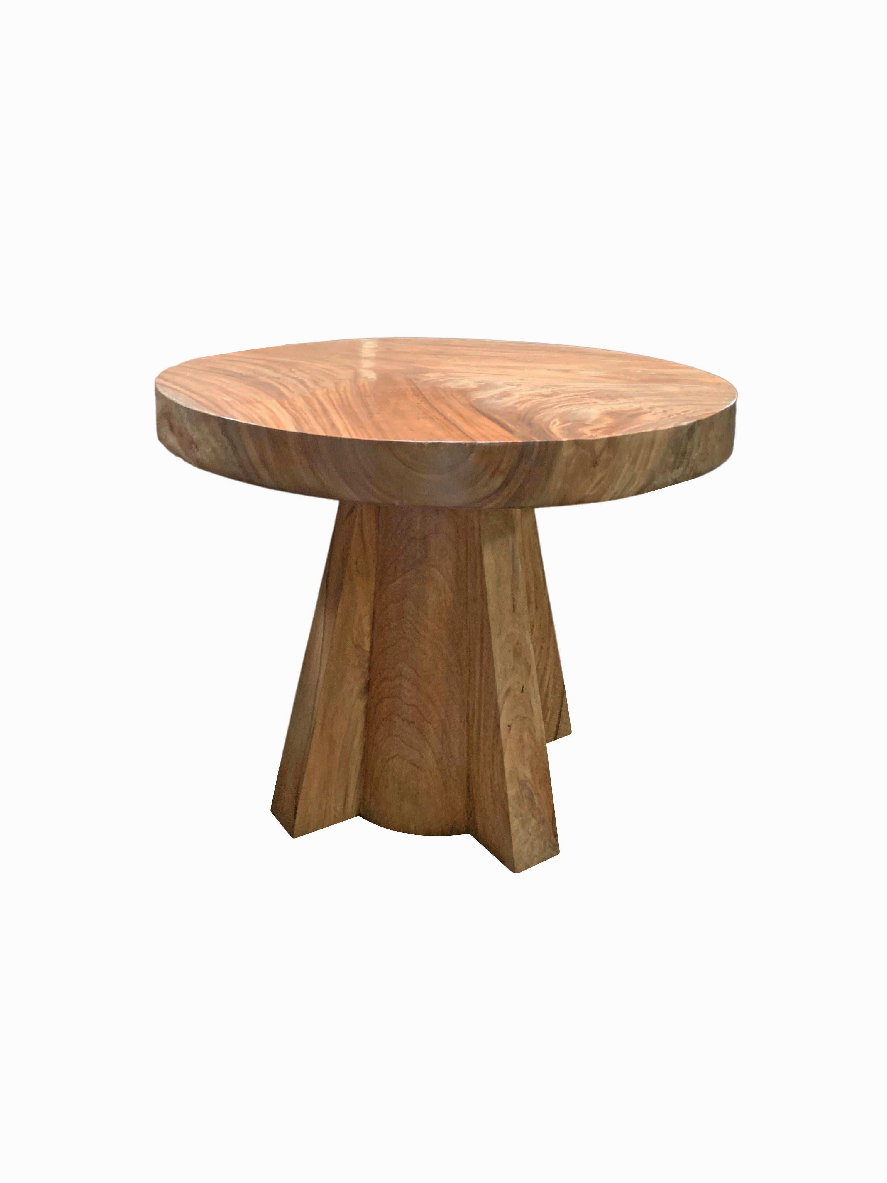 A wonderfully sculptural round side table. Crafted from solid suar wood with wood textures and shades throughout. The table top was crafted from a single block of wood supported by angular legs. An organic object to bring warmth to any space.