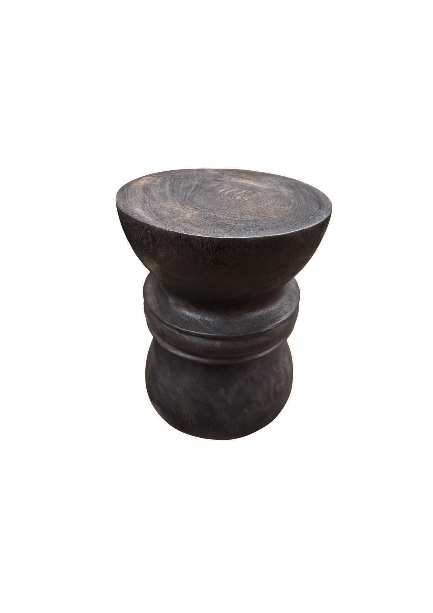 Cette élégante table d'appoint présente une finition expresso brun foncé saisissante, obtenue grâce à un processus méticuleux de brûlages multiples qui approfondissent les tons riches et terreux. L'artisanat unique est mis en valeur par les détails