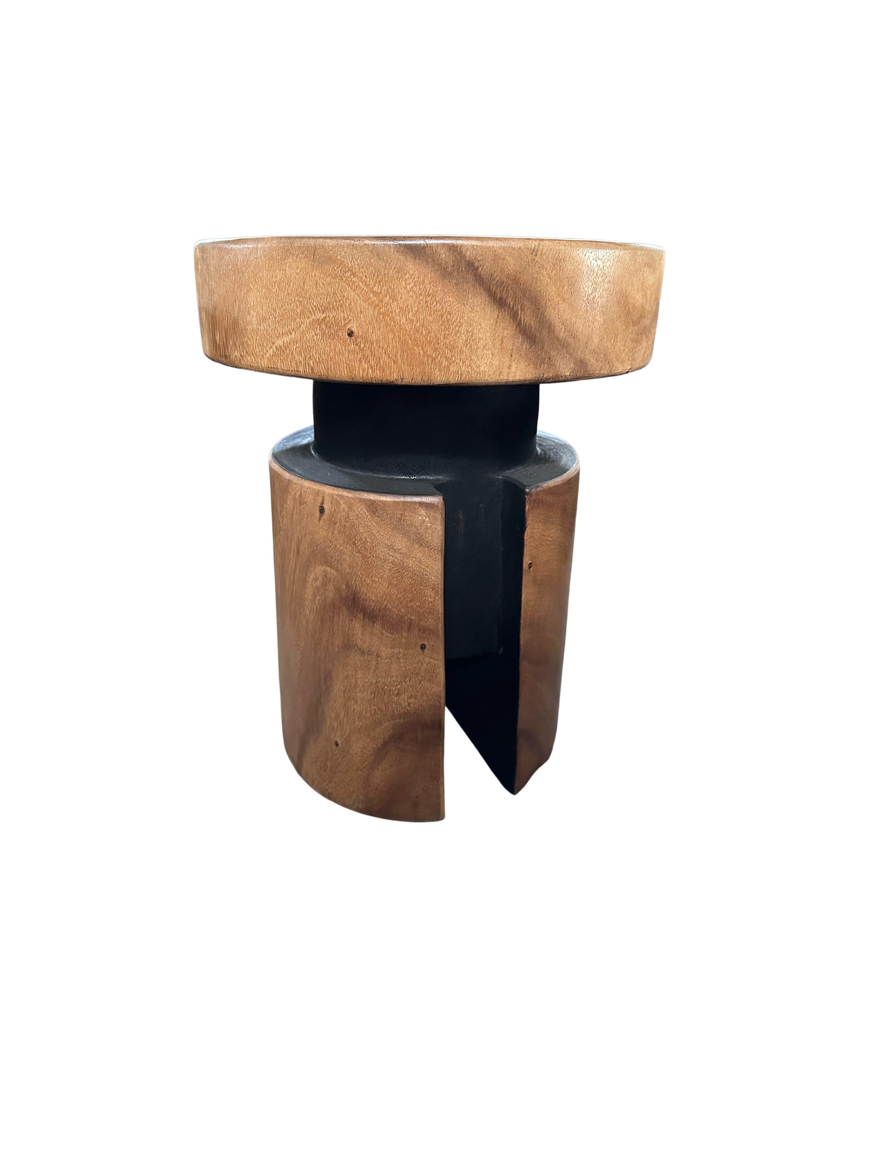 A wonderfully sculptural side table crafted from Suar Wood. Its curved edges and abstract form add to its charm. The perfect object to bring warmth to any space. This table features a carved hole at its base as well as a mix of burnt and natural