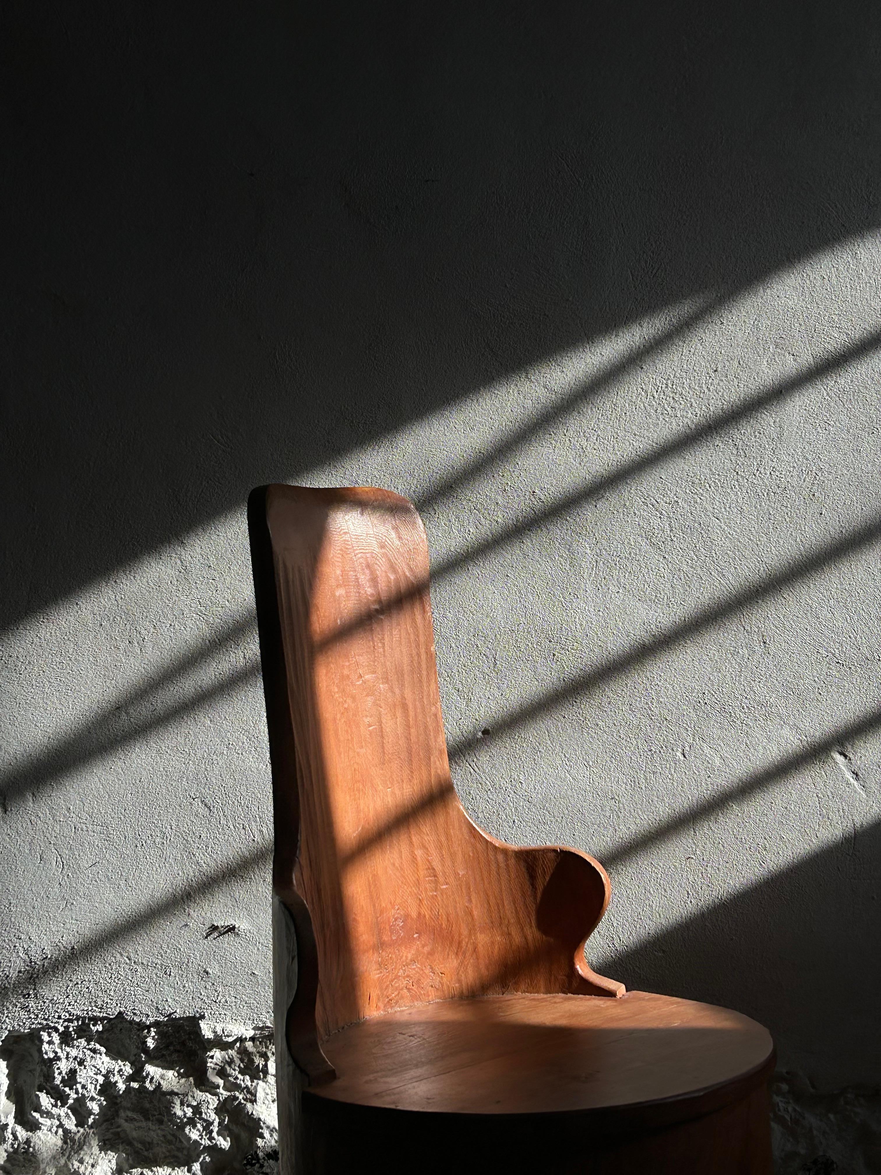 Beautiful Swedish kubbestol likely originating from the Dalarna region of Sweden, known for its rich folk art traditions and distinctive woodcraft, carved from a single solid tree trunk, circa 1900-1920. This piece combines traditional Nordic folk