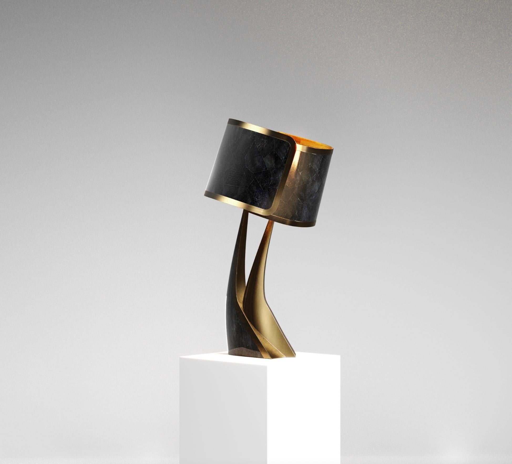The Chital III Table Lamp by Kifu Paris is a sleek and sculptural piece, inlaid in a mixture of bronze-patina brass and black pen shell. The chiseled legs, which are an iconic shape within the KIFU PARIS universe, morph into the solid shades that