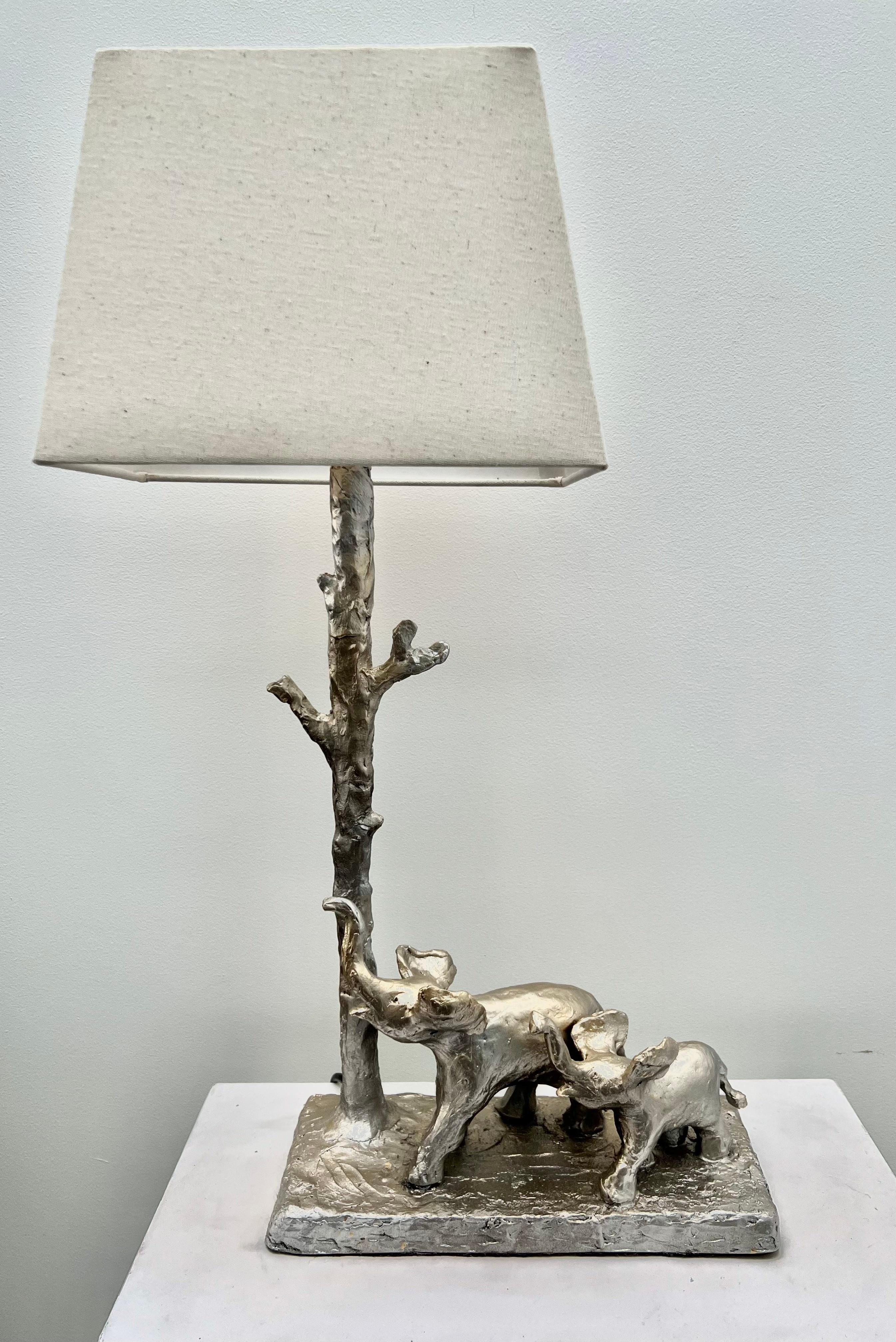 A  Lampe de table sculpturale représentant une mère et son bébé éléphants se promenant joyeusement avec leurs trompes en l'air . Une œuvre d'art fonctionnelle,  Fabriqué à la main, moulé et coulé dans une résine légère. 
Toutes les pièces de la