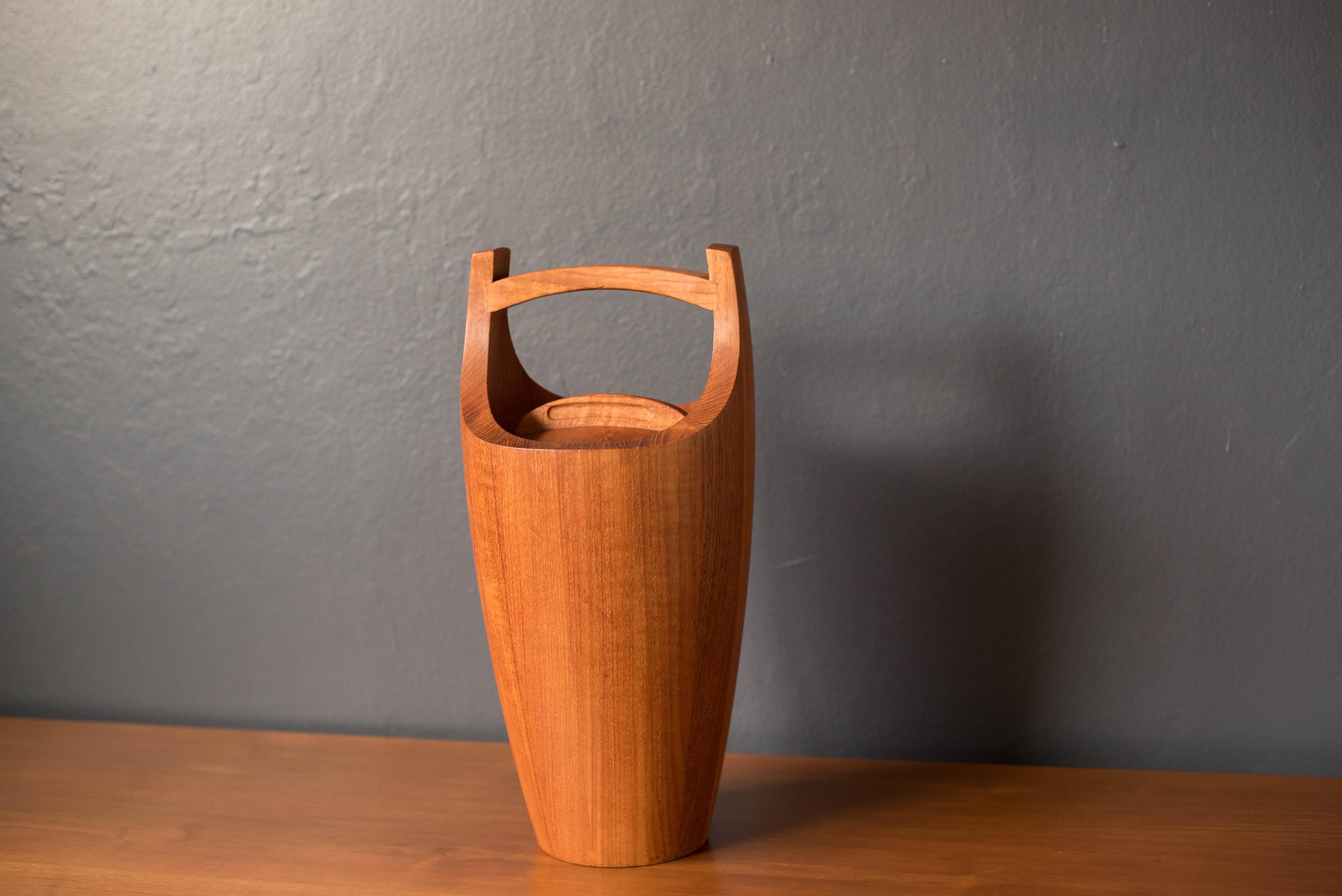 Mid Century Modern Dansk ice bucket wine cooler designed by Jens Harald Quistgaard, circa 1960's. This collectible piece is made of solid teak and features the original orange interior liner and sculptural carrying handle. The perfect decorative